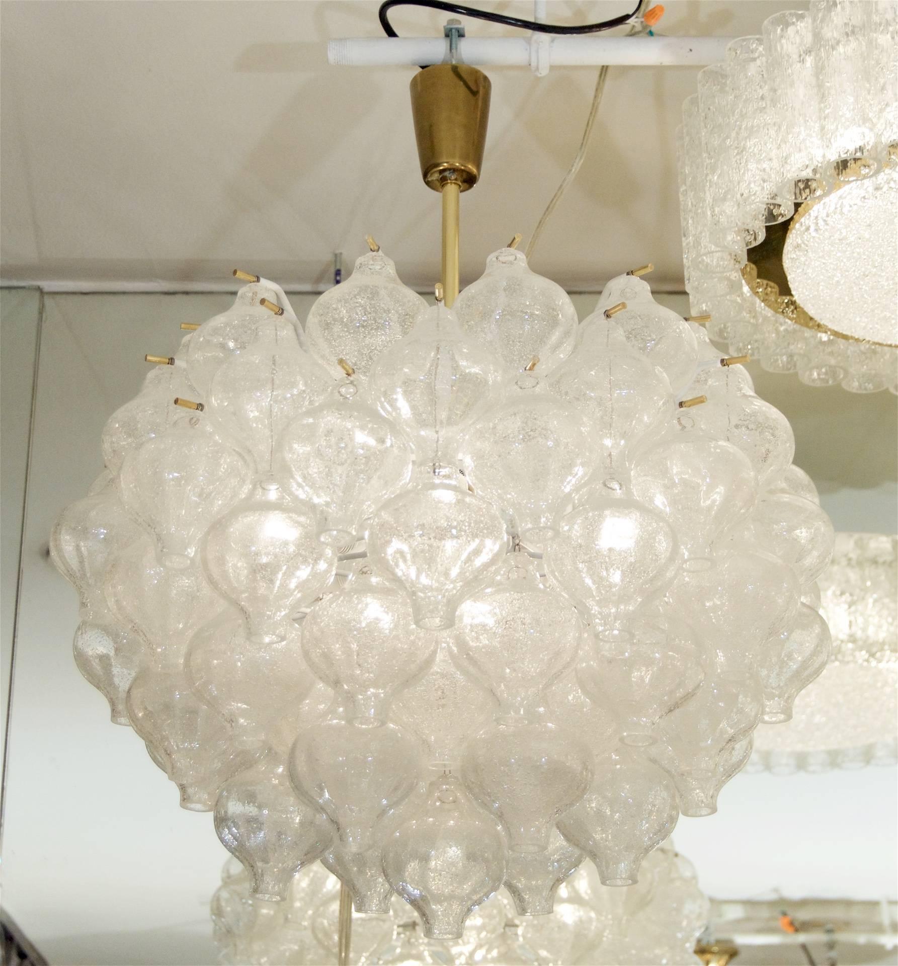 An exceptional Kalmar Tulipan glass pattern chandeliers, having 71 individually hung pieces of glass. Each piece of handblown glass is wire suspended on brass pins, with the central body in enameled white.

Twelve E-14 base bulbs radiate from the