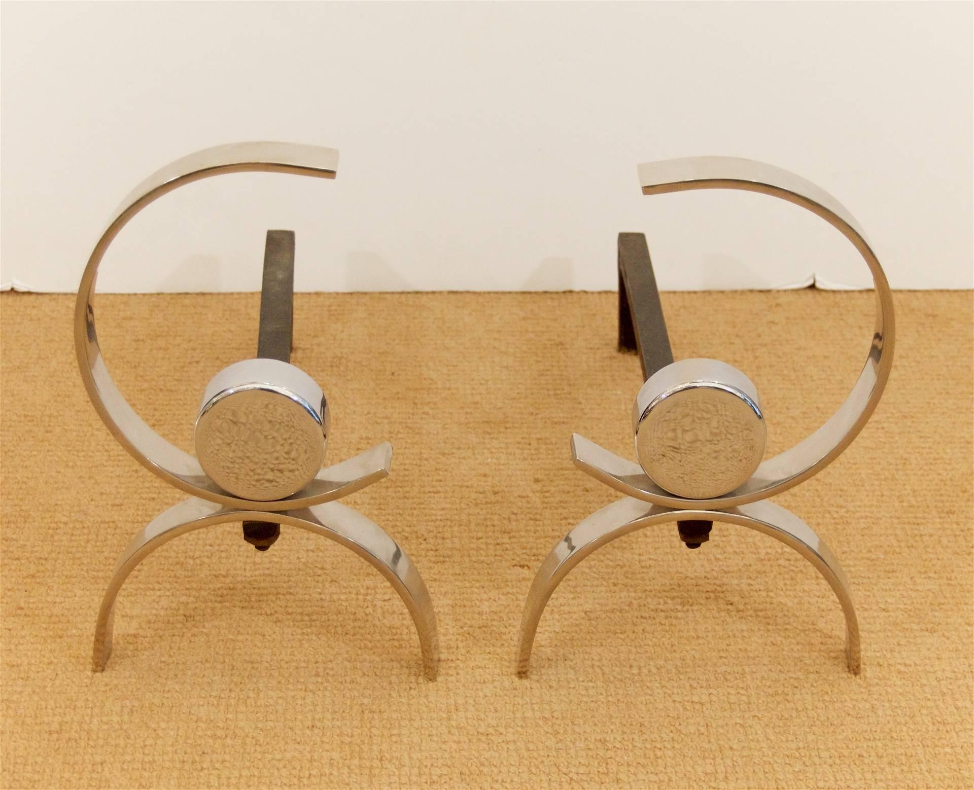 Pair of elegantly formed arc-shaped chrome andirons in the style of Donald Deskey.