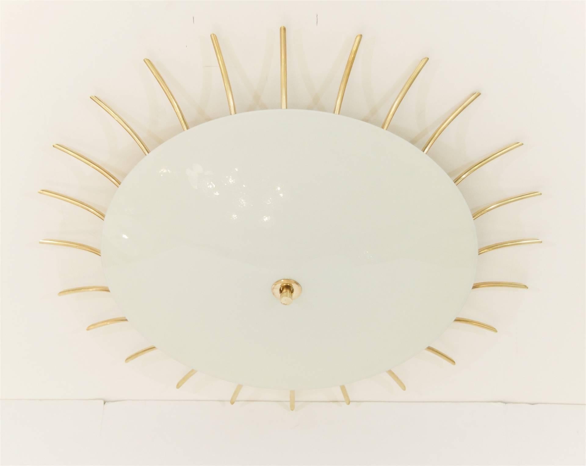 Grand scale flush mount with individual pieces of arced brass radiating around a glossy opal glass domed center plate.

Takes three medium base bulbs up to 60 watts per bulb. New wiring.