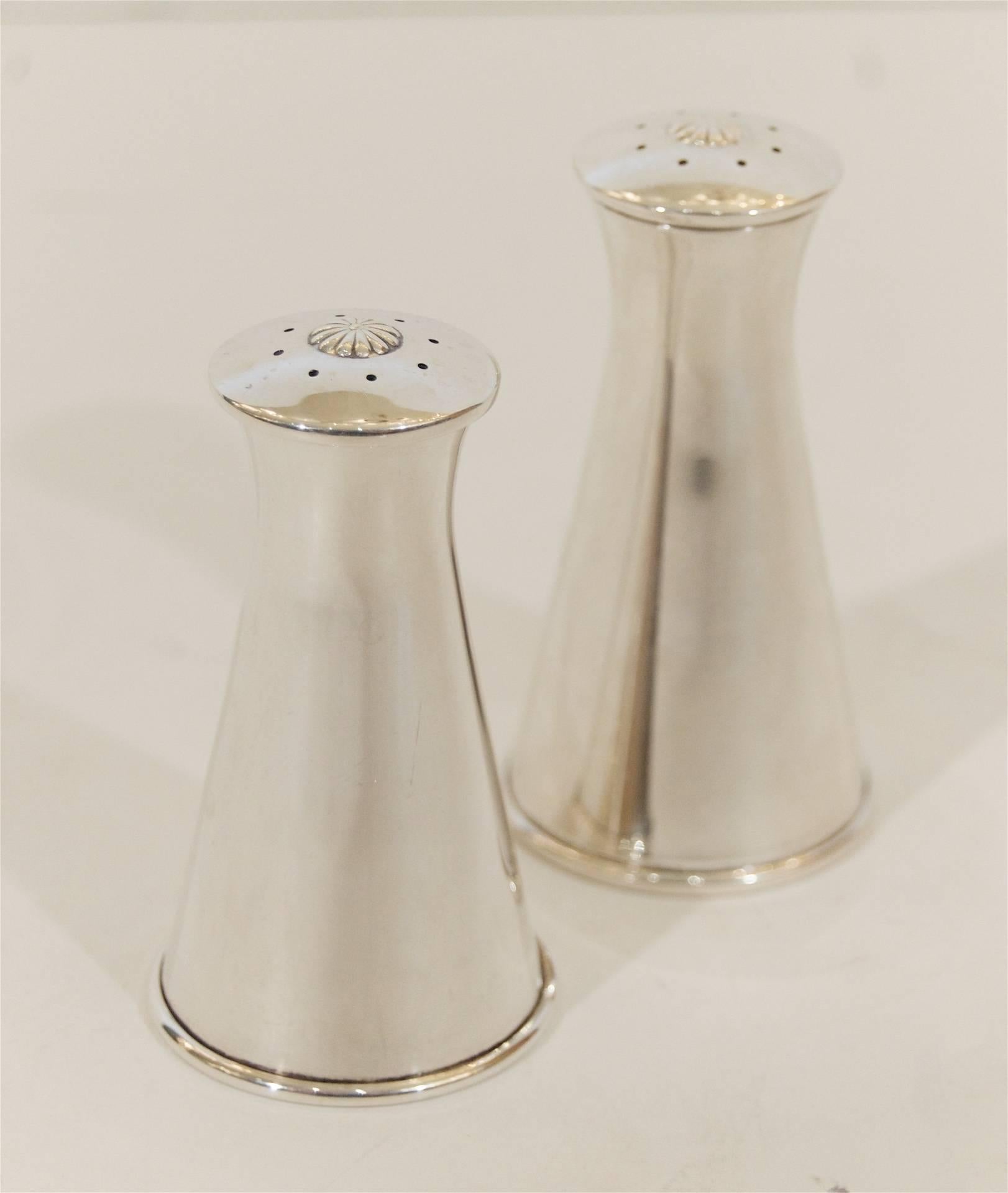 A pair of midcentury Reed & Barton matched salt and pepper shakers in sterling silver, an elegant profile of concave and convex curves. Floral detail on top of both shakers. Pattern X33.
