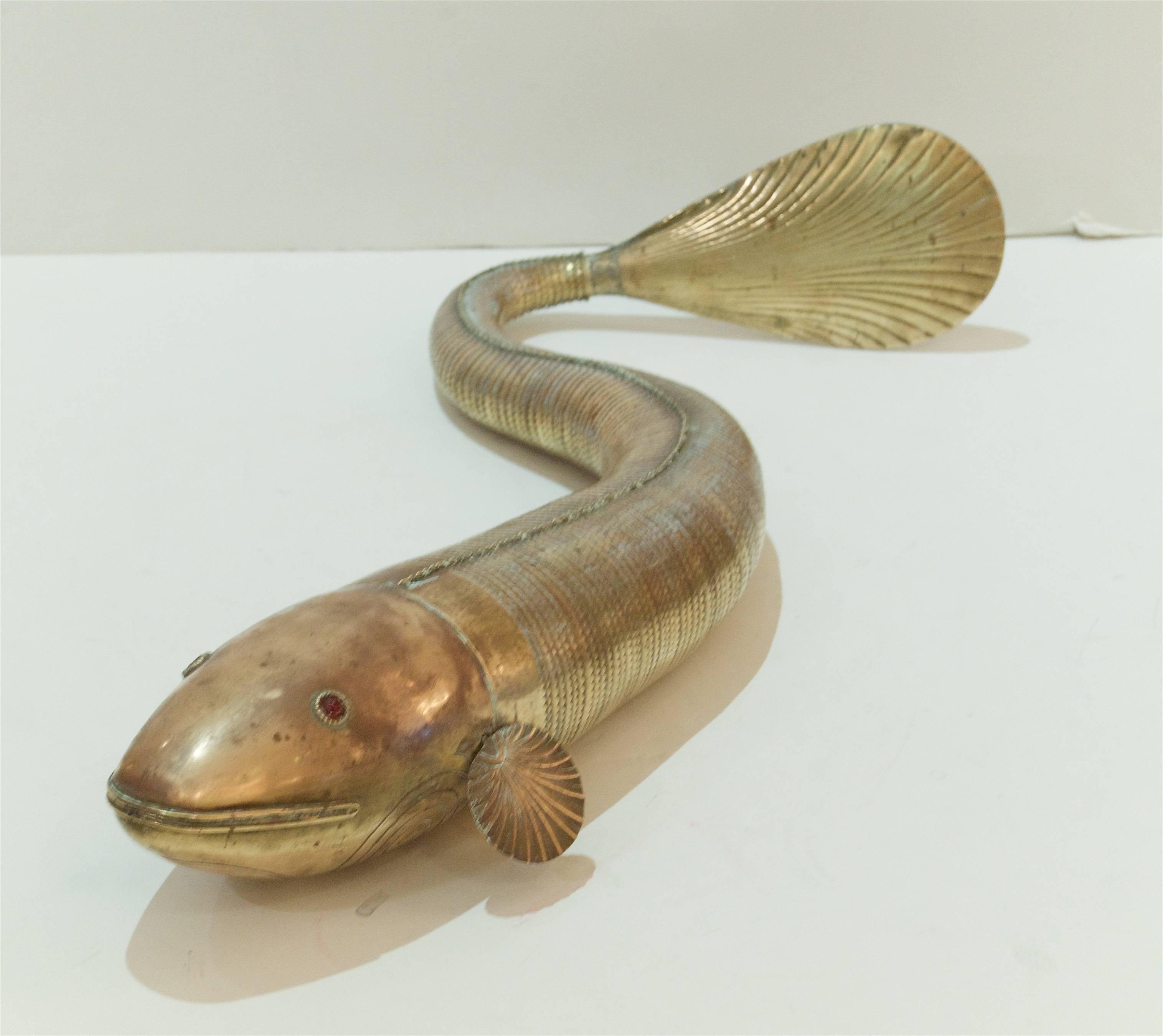 Dramatic and massive articulated fish sculpture in the form of a koi of brass and copper with paste glass eyes. Body of fish is fully moveable laterally.

Measurements are of length fully extended.