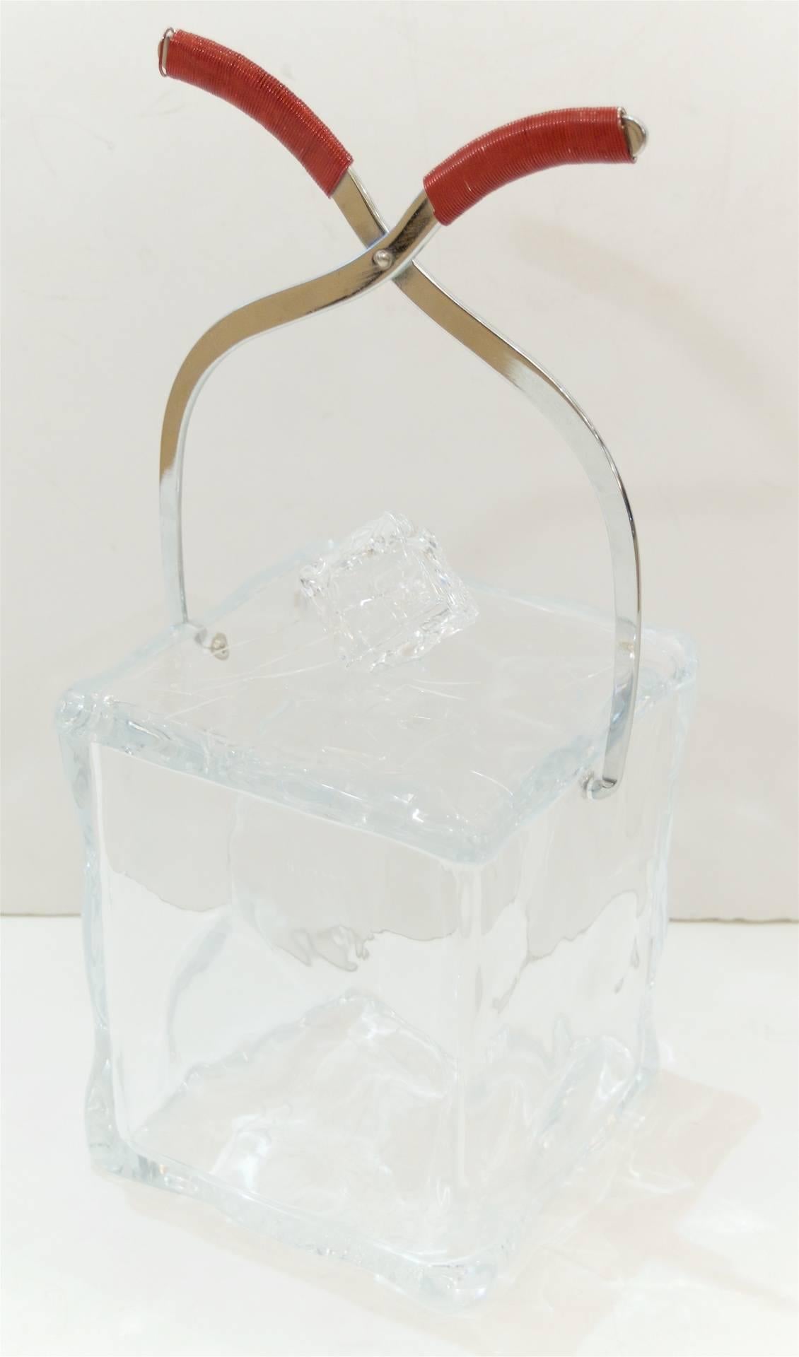 Unusual Lucite ice bucket has the look of an ice cube with chrome ice tongs, the handles made of wrapped red metal. A wonderful unique addition to the bar.