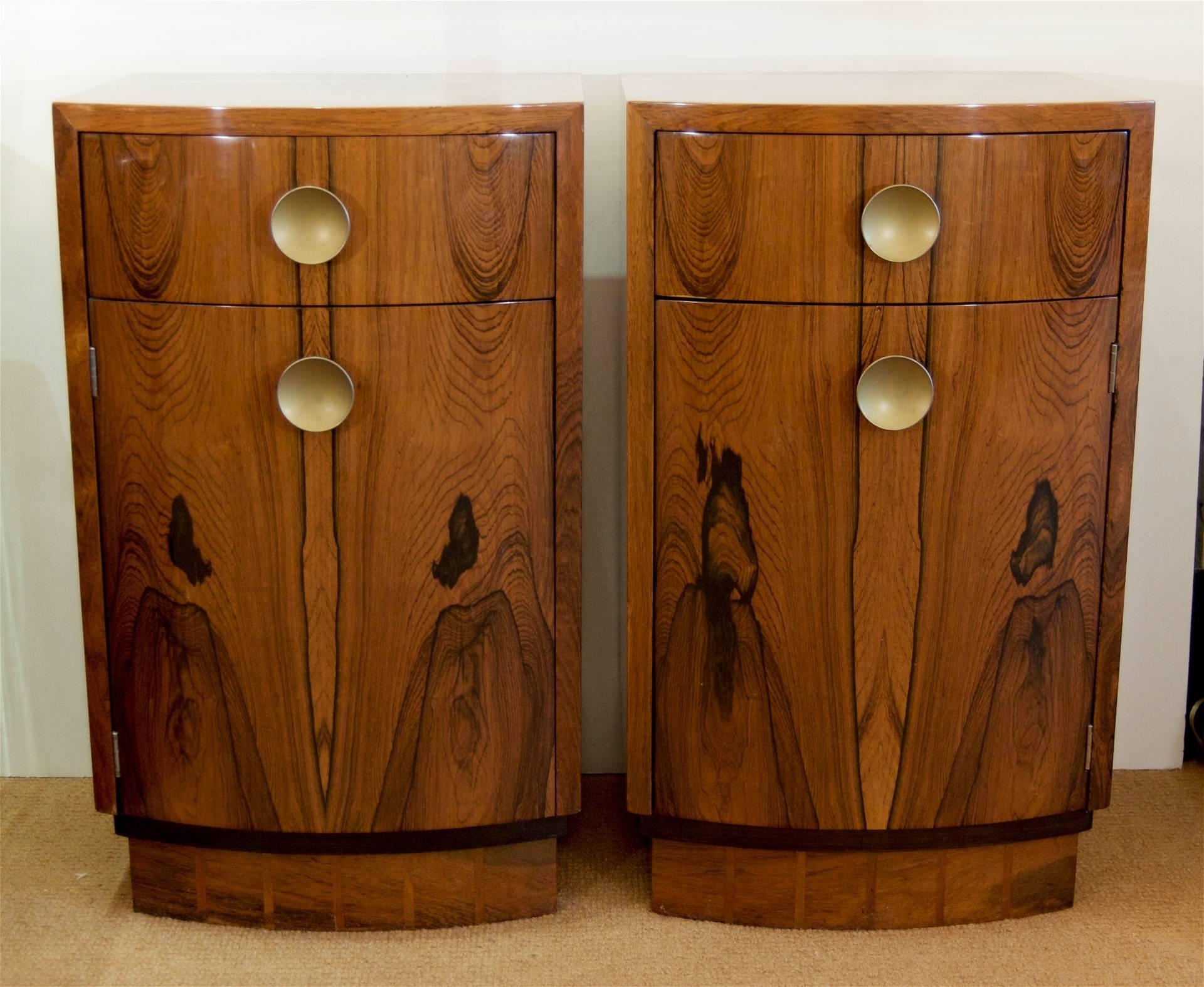 Pair of Art Deco bookmatched rosewood veneer Gilbert Rohde nightstands by Herman Miller. Each nightstand has a drawer and interior compartment with circular brass pulls;

Pedestal base features interesting geometric striped inlay. Interior in
