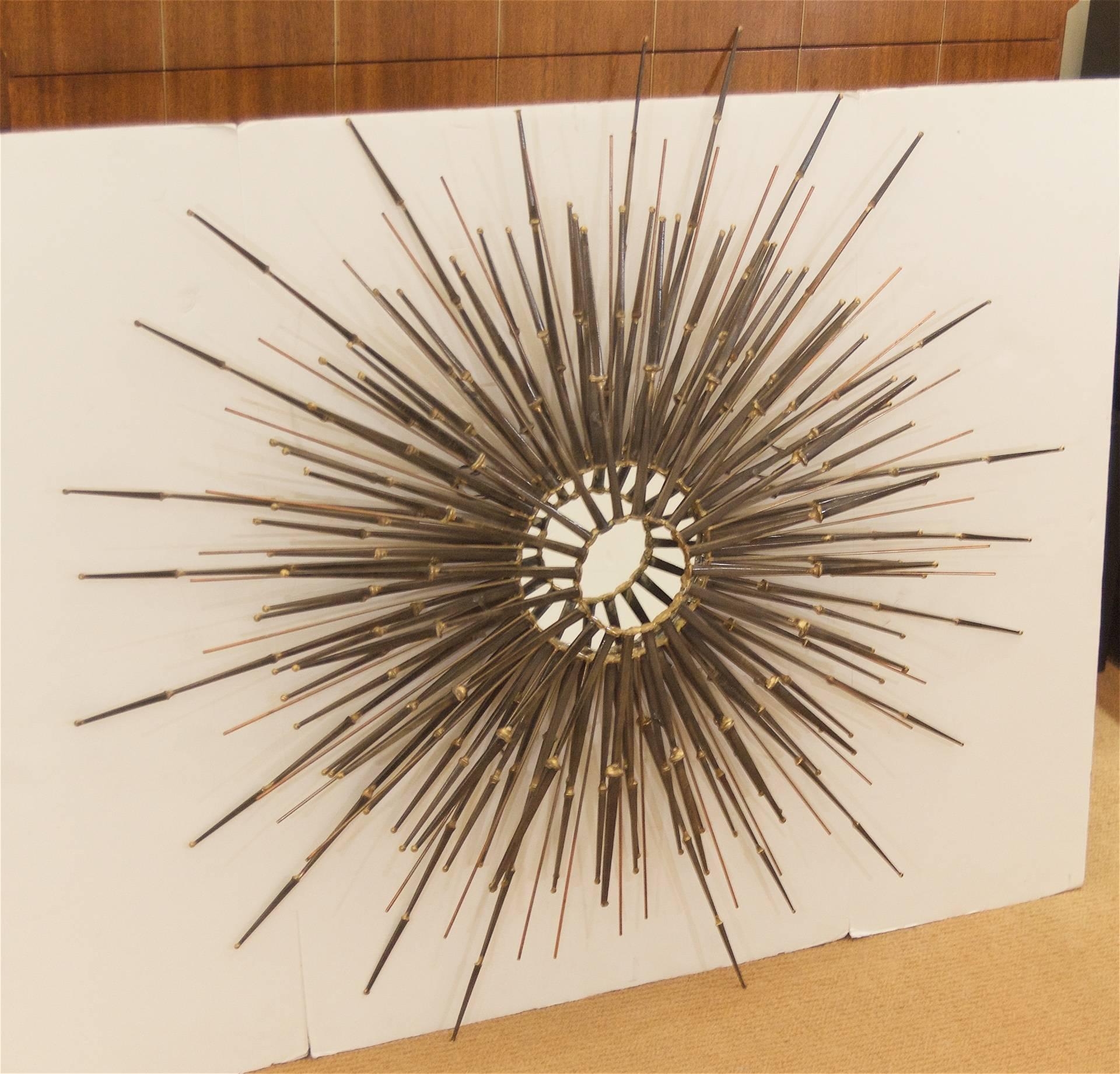 Grand scale sunburst wall hanging comprised of welded masonry nails and metal rods, in a mix of original steel and gilt finish accenting. New central mirror

Signed B.H. Kelvin '74.