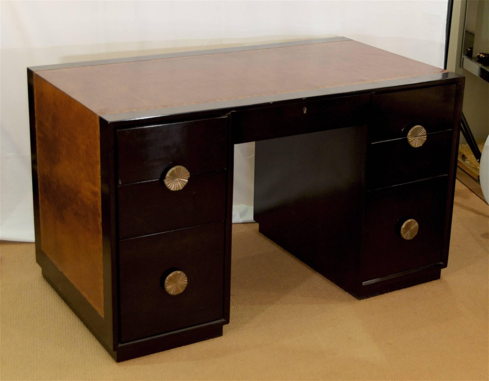 Mid-Century ebonized desk by Charak Modern with camel colored leather top and embossed Greek key detailing, attributed to Tommy Parzinger. Each of the six drawers have substantially sized sunburst brass pulls. Finished on all sides, obverse of desk