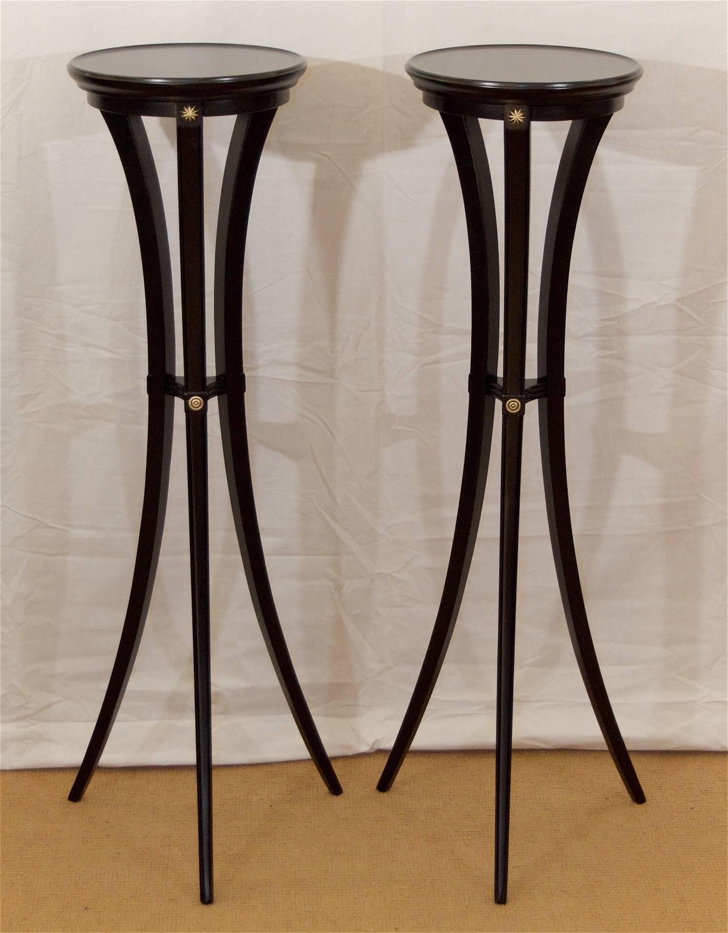 Pair of classically shaped tall plant stands or display pedestals, the gracefully curved legs accented with fluting and gilt detailing. Newly lacquered in satin black, re-gilt and patinated detailing.

Diameter listed is at base of legs; diameter