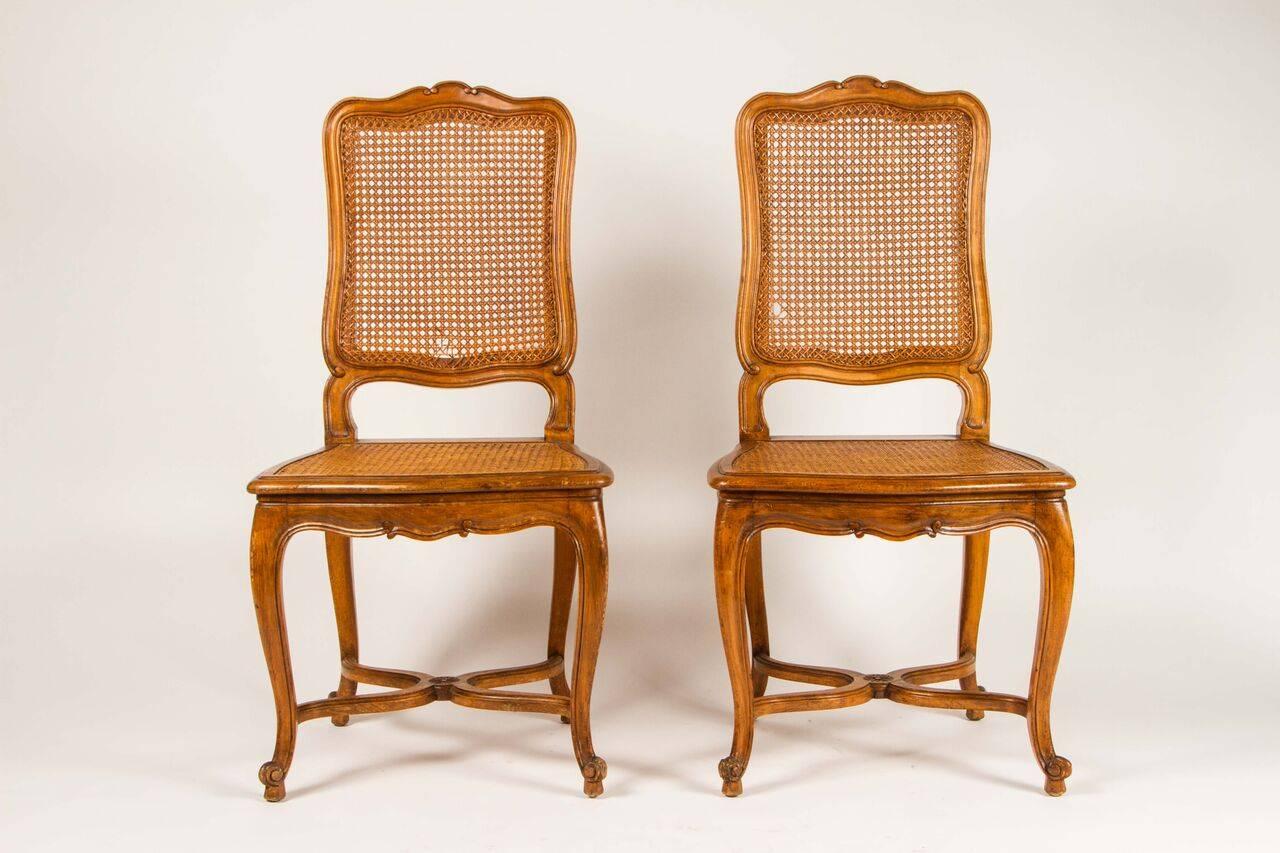 This lovely pair of 19th century chairs are in the Louis XV style. With cane seats and backs, the legs are supported by a delicate serpentine stretcher. 
These chairs would be perfect in a bedroom, or a library.