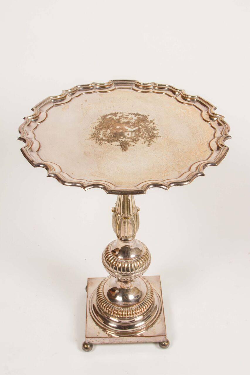 Stunning sterling silver guerdon table from the Dorothy Chandler estate. Top has an elaborately detailed edge and the center etched with a crest. The center is adorned with acanthus leaves in a traditionally ovoid shape, sitting upon a square base