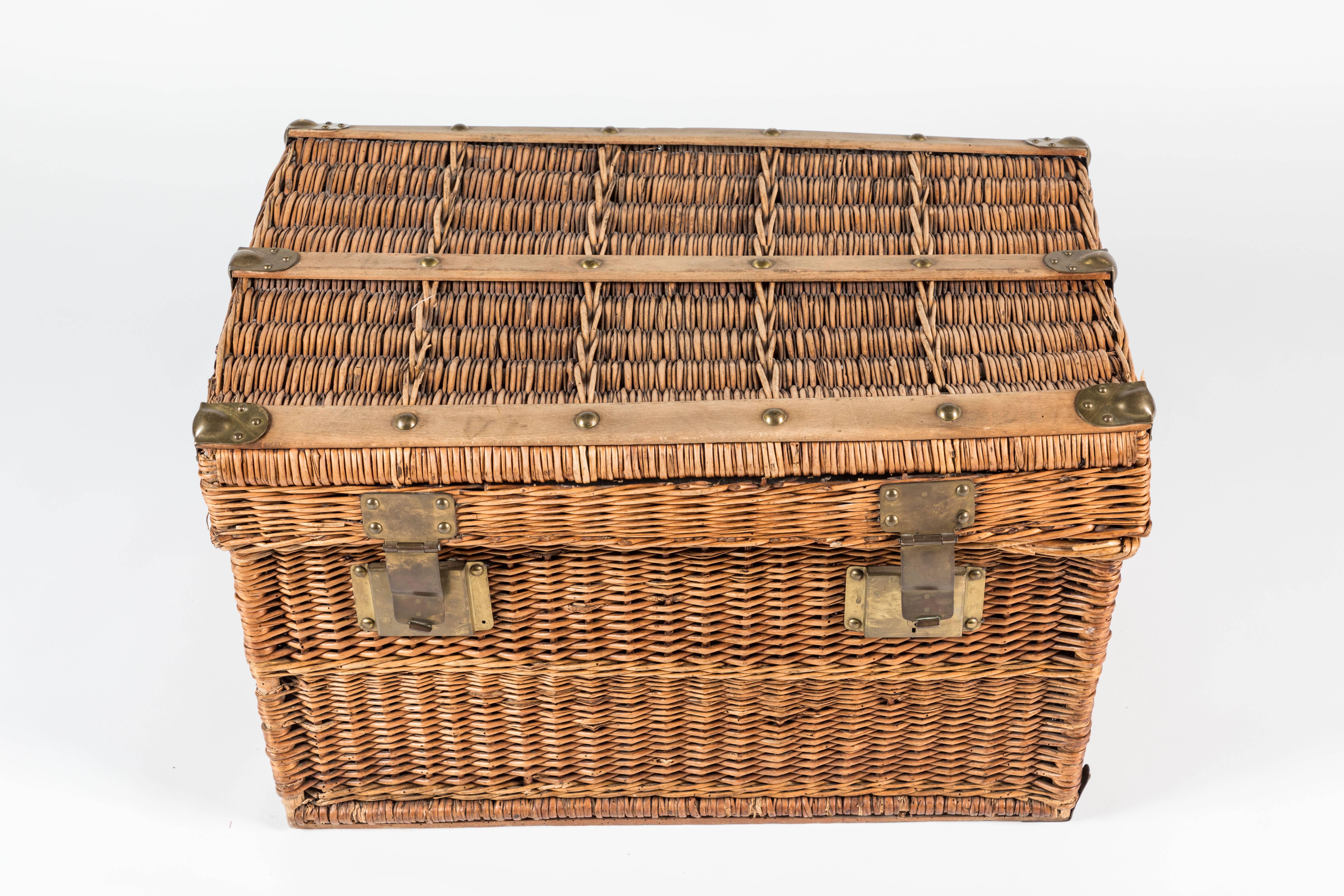 Antique Campaign-style basket from Kenya made of rattan and wicker with a wooden frame. Features rawhide strapping and brass hardware. Canvas lined. 
This piece provides a stylish solution for additional needed storage and would make a great toy