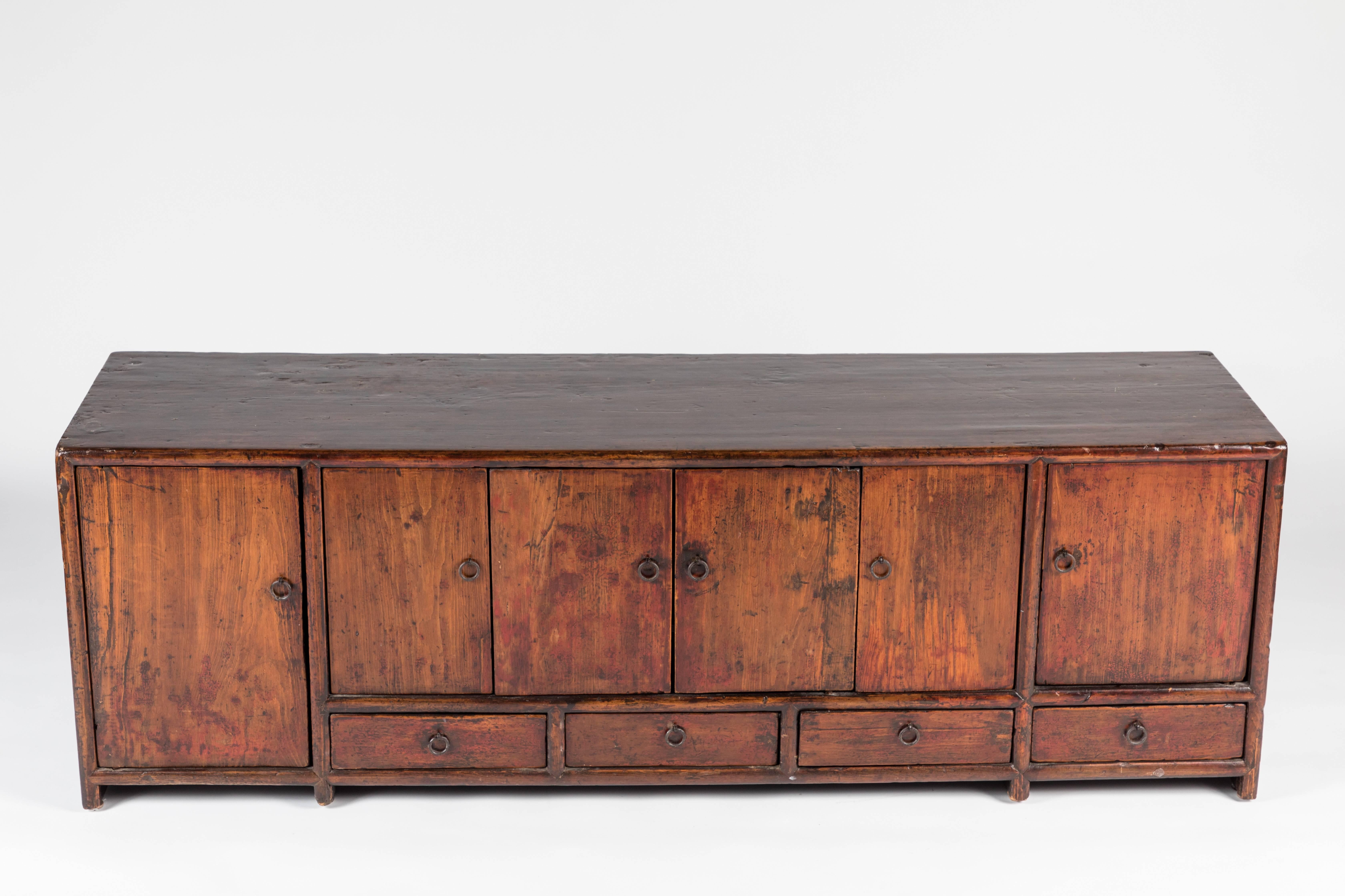 A unique sized antique Chinese wooden low console produced circa mid-late 19th century, which includes six doors, above four drawers, with pulls in brass. Good antique condition, with some wear as well as age appropriate patina to brass hardware.