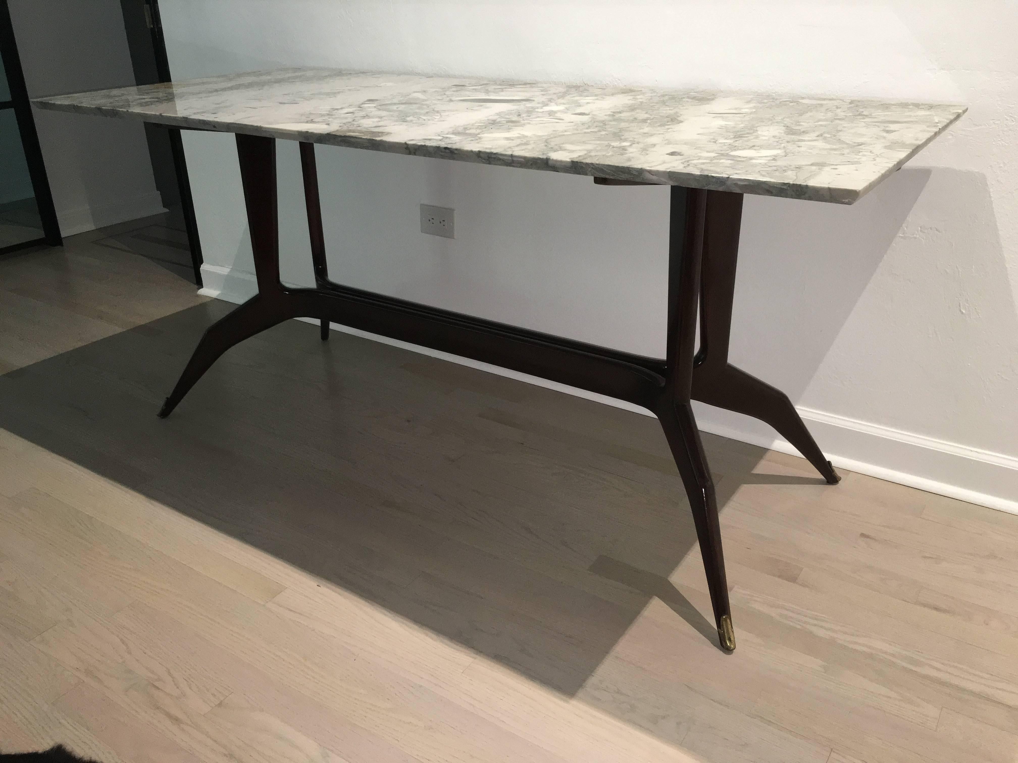 This wonderfully chic Italian table is sculptural and unique. Rich marble top and brass sabot clad feet. This table is narrow and works best as a console, desk or small dining table.