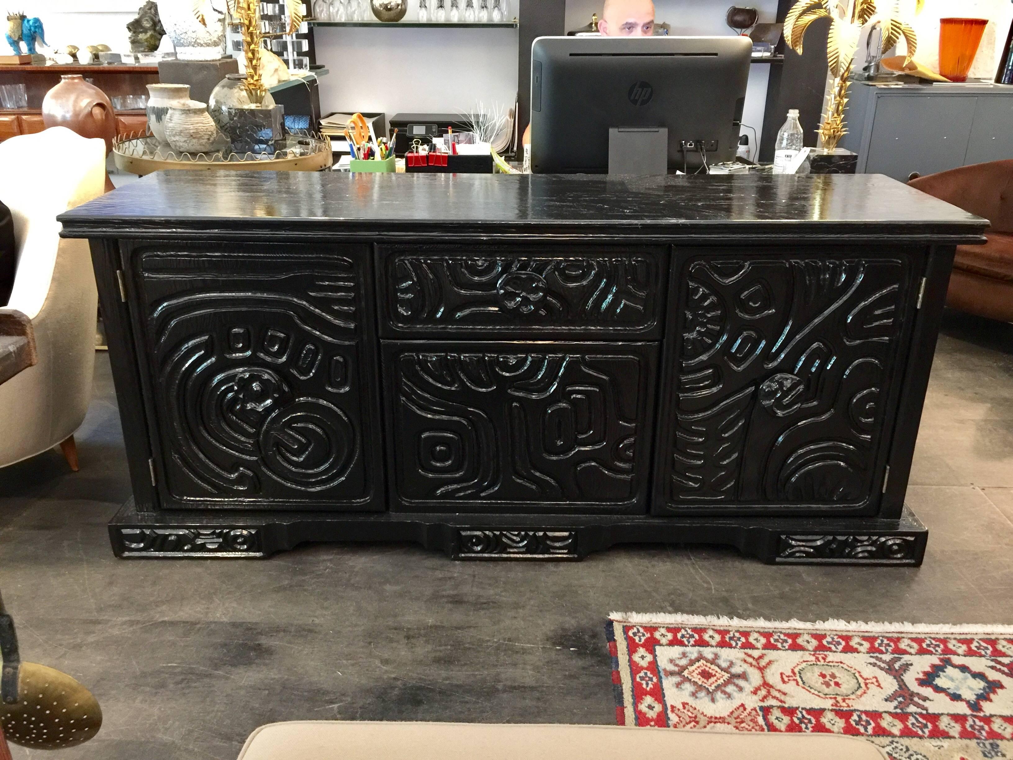 Lacquered in a black piano finish the brutal carved wood design is almost tribal and artistic (reminiscent of Louise Nevelson). There are two doors and a single drawer to centre.

Note: We have two matching console tables available. Please see our