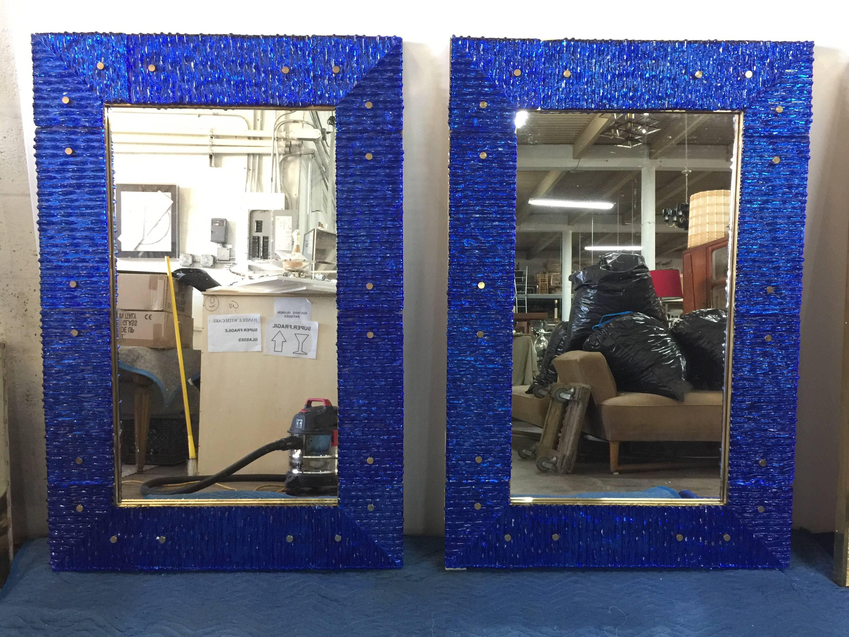 Beautiful heavy brass trim to this Murano glass clad mirror, screws and interior frame all in brass. This blue is vivid with rich cobalt blue hues. Ribbed Murano glass pieces throughout the entire edge frame. Stunning pair - priced and sold