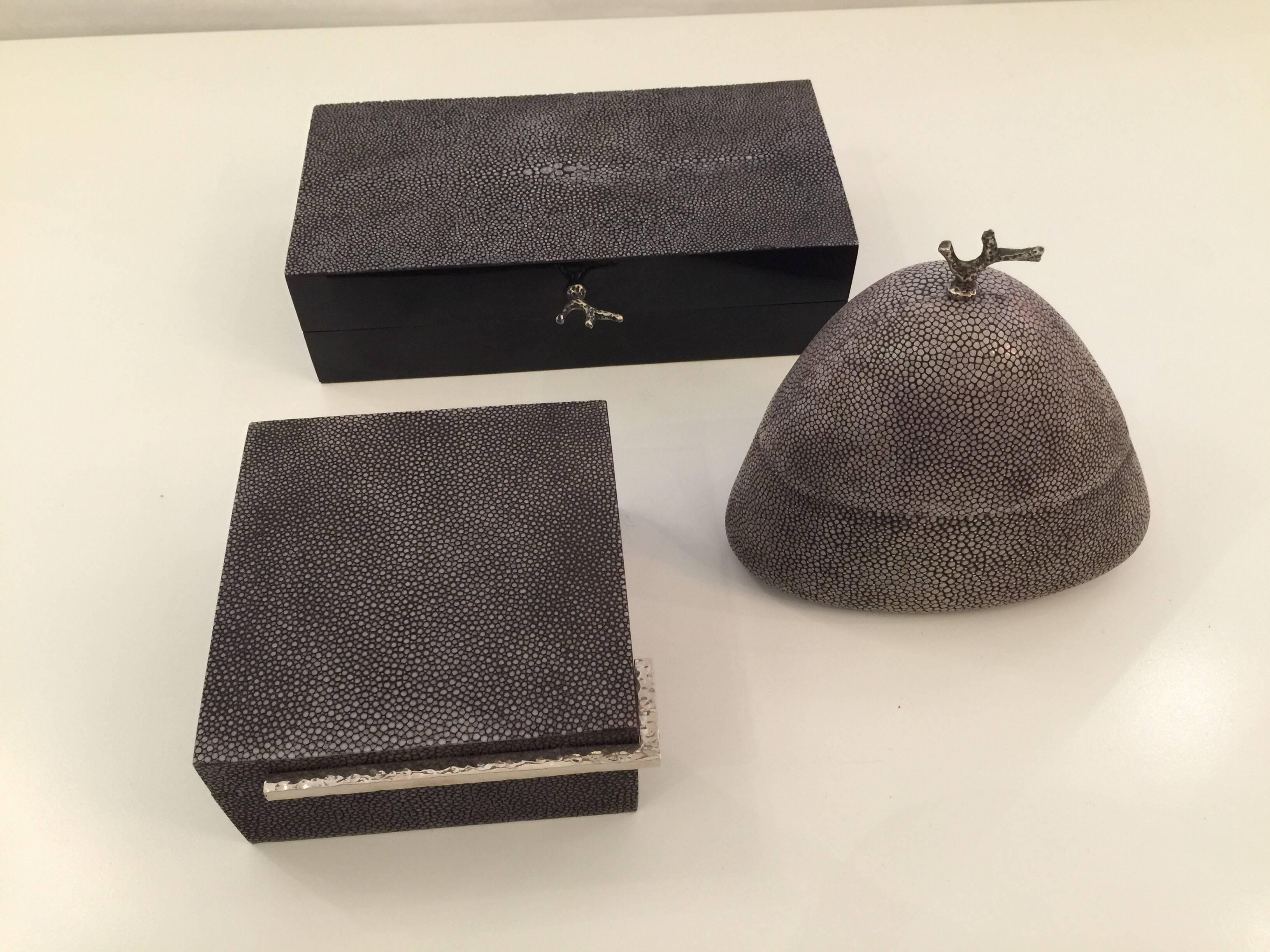 This is a lovely matching set of three grey toned shagreen covered boxes. The domed top box features a silver plate coral branch handle. The large rectangular box also has a coral branch handle. The square box is more linear. Interiors are lined
