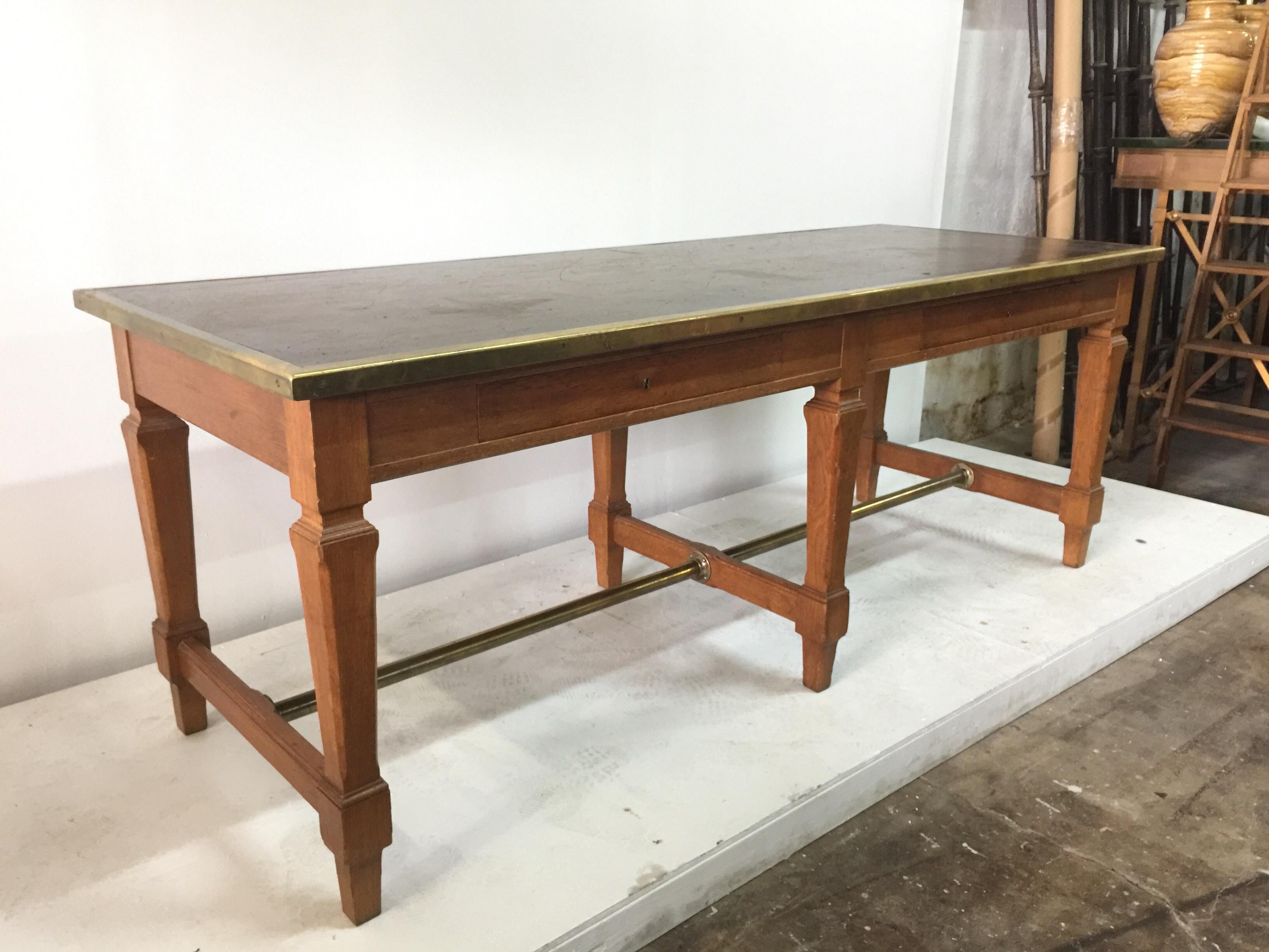 Equipped with two front drawers, original key (single key locks both drawers) and brass molding which frames the top in aged cognac leather. Brass stretcher at base. Exceptional design very much after Jacques Adnet. This piece is great scale as a