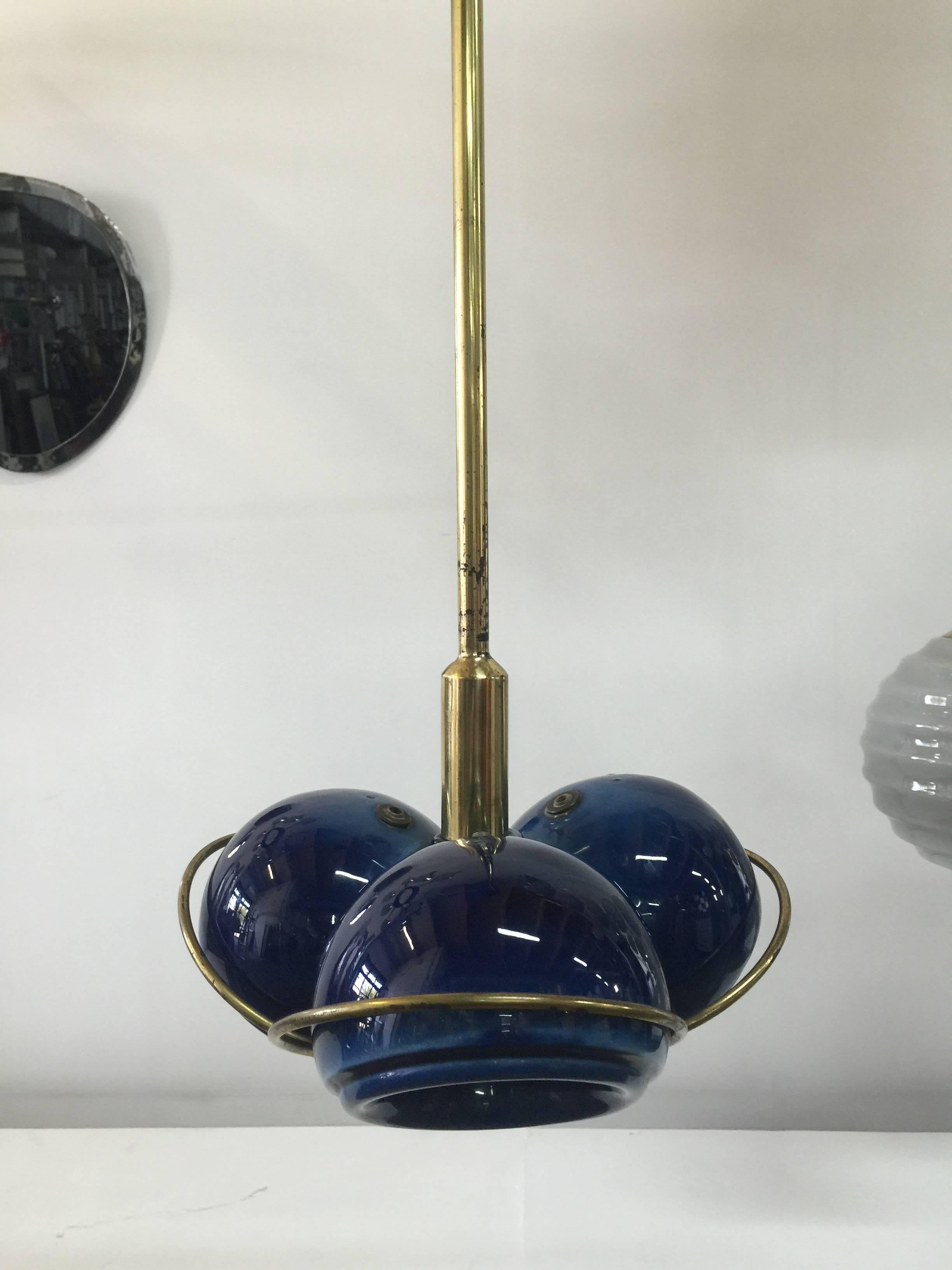 Decked out with brass accents and stem/ ceramic canopy, this all original rich blue glazed ceramic hanging light features three lights. Never seen another like this beauty.