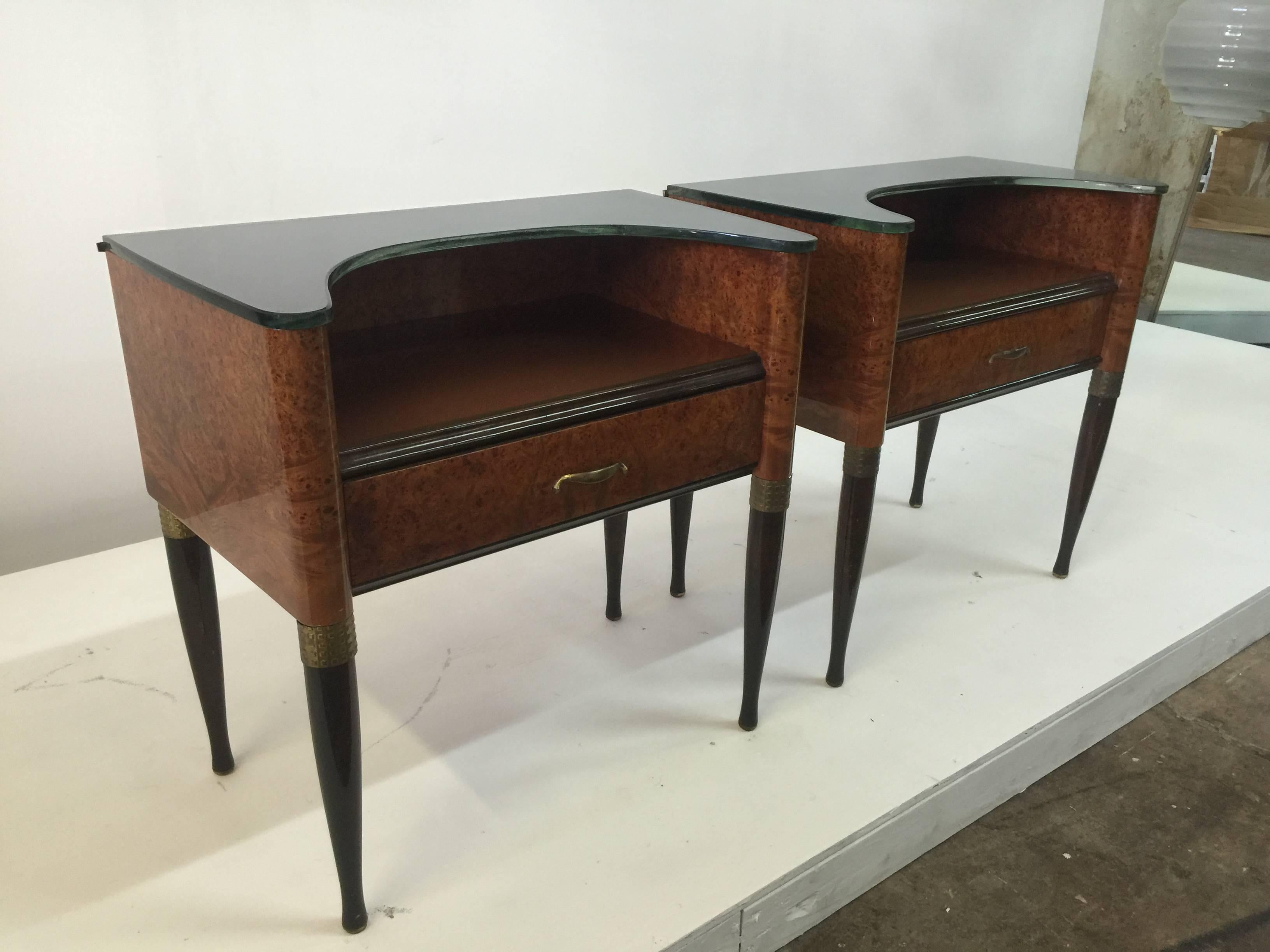 These are rare! A wonderful pair of two-tiered night tables. Single drawer each with original brass hardware and accents. Glass is all original on both levels, top shelf level is a curved glass for added flair! Burl wood and walnut.