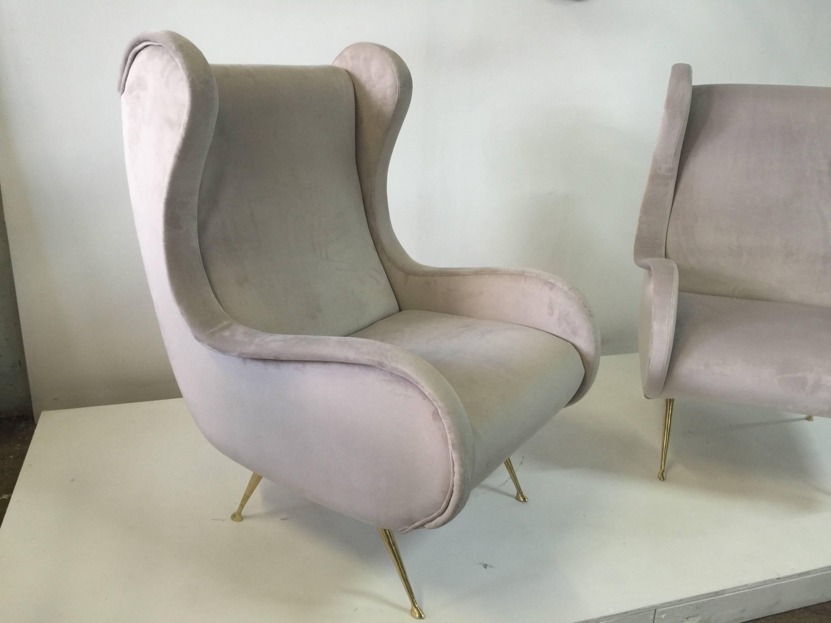 Finished in a soft beige fabric and brass feet, these winged armchairs are very stylish.  This item is currently located in our Miami showroom.