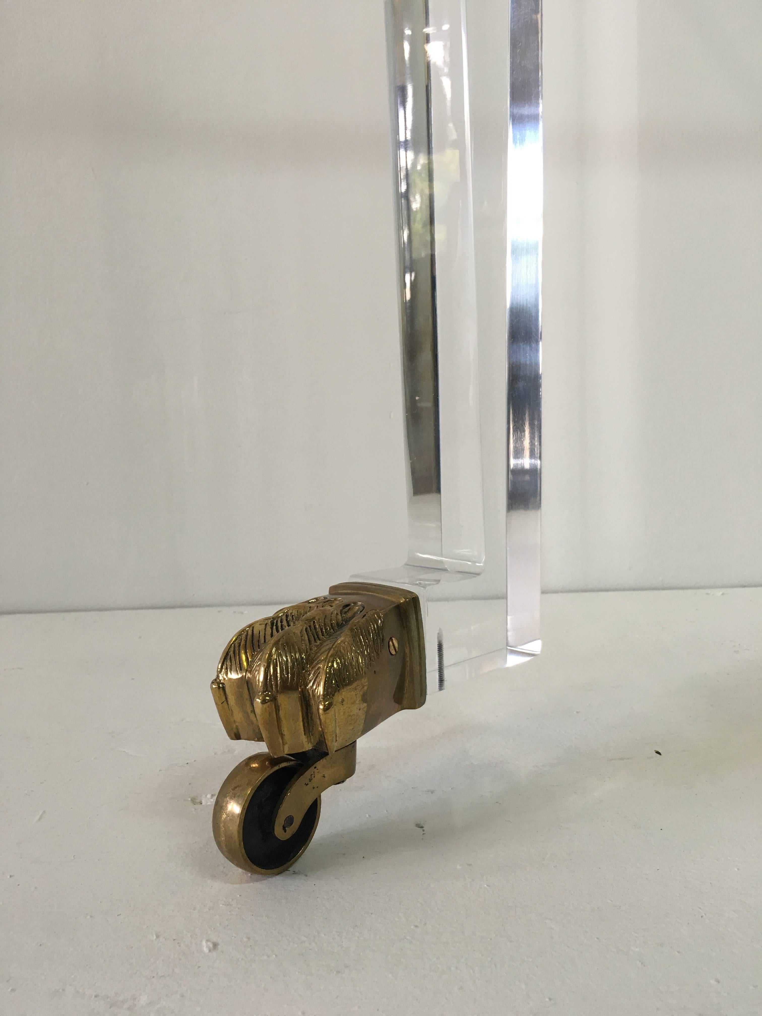 Unique piece, custom designed with vintage lion’s feet brass castors. The wall-mounted sleek acrylic console has facets and tapering to accentuate its rare beauty.