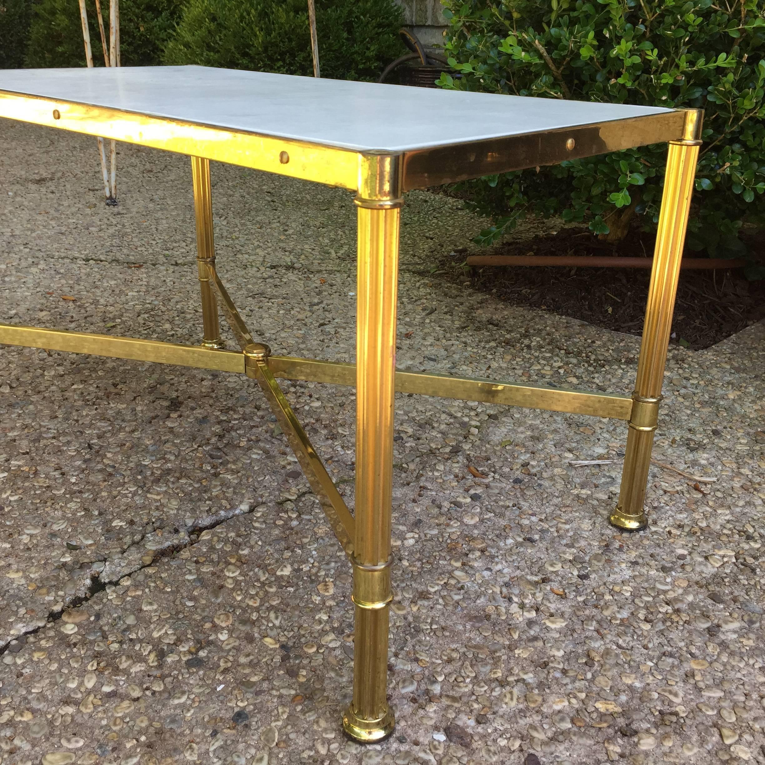 This lovely Jansen attributed brass framed rectangular shaped table with a natural parchment top in neoclassical style. It is a wonderful side table.