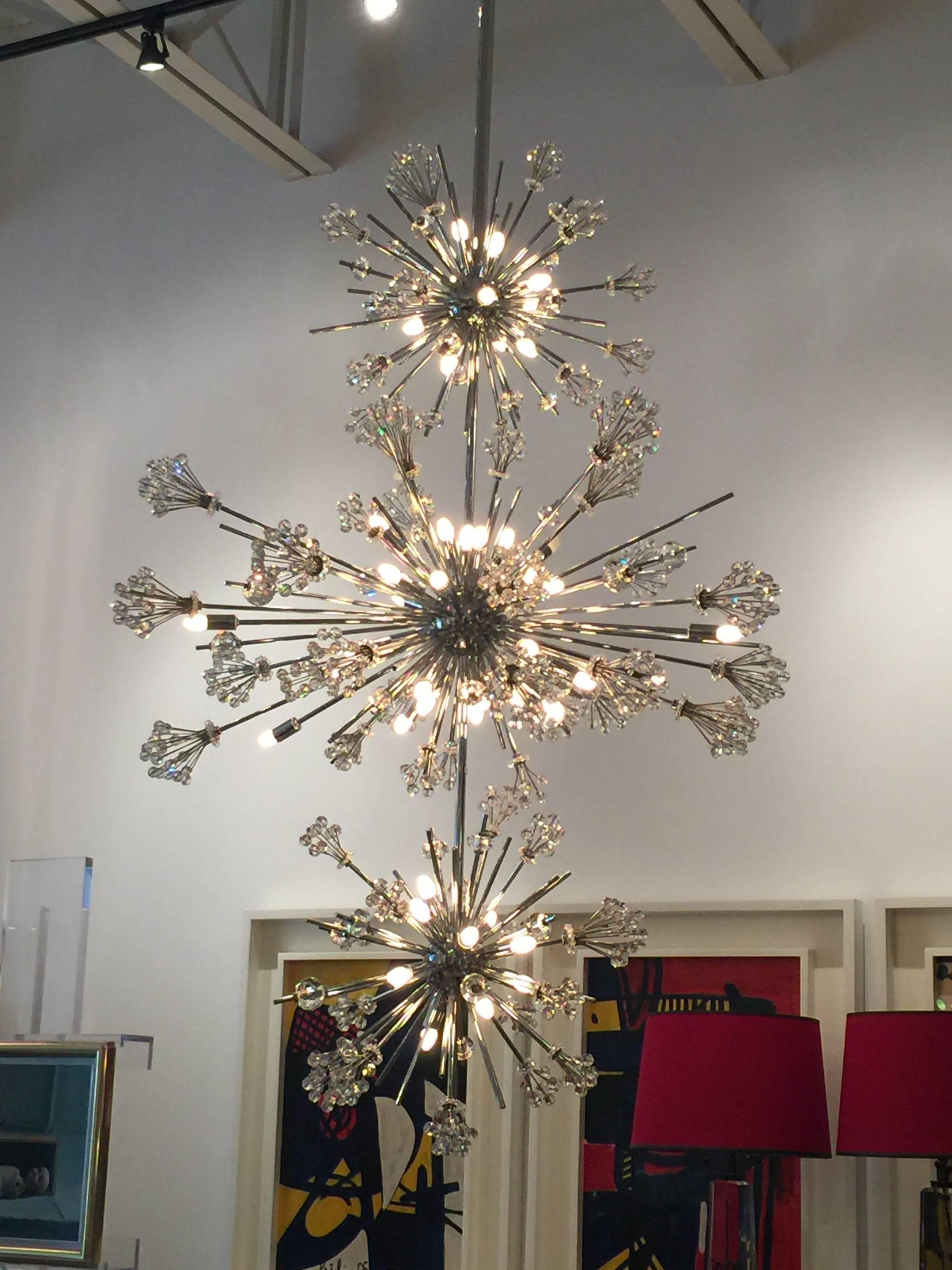 The chandeliers look like crystal constellations with sparkly moons and satellites spraying out in all directions. They are a symbol of the Gilded Age as well as a symbol of the Space Age.

This fixture features three central chrome orbs that