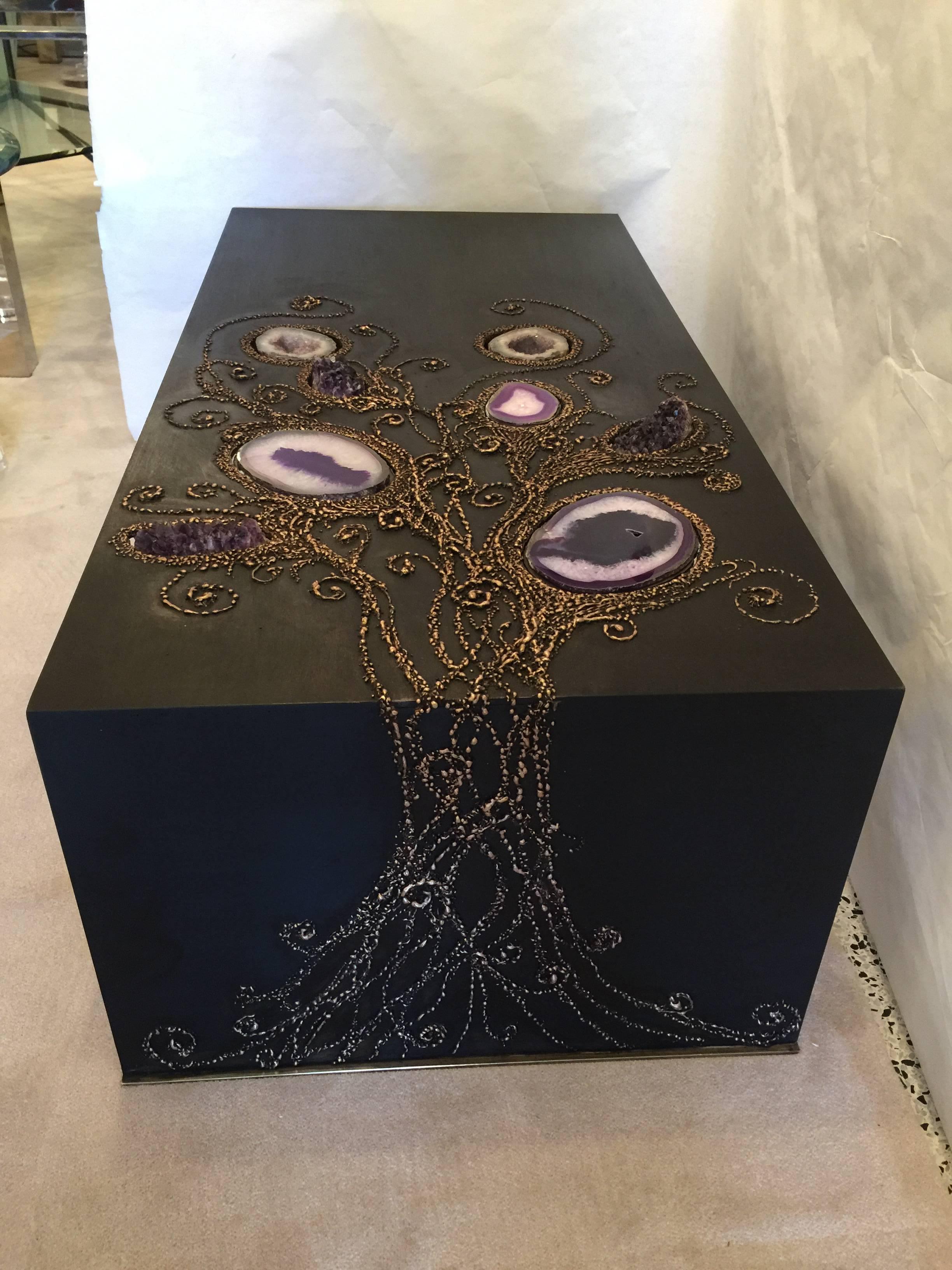 This true labour of love designed cocktail table boasts encrusted natural agate stone, amethyst chunks and quartz eggs. All rich bronze patina and brass trim base accent, the glimmer factor is truly on display in this one-of-a-kind custom table by