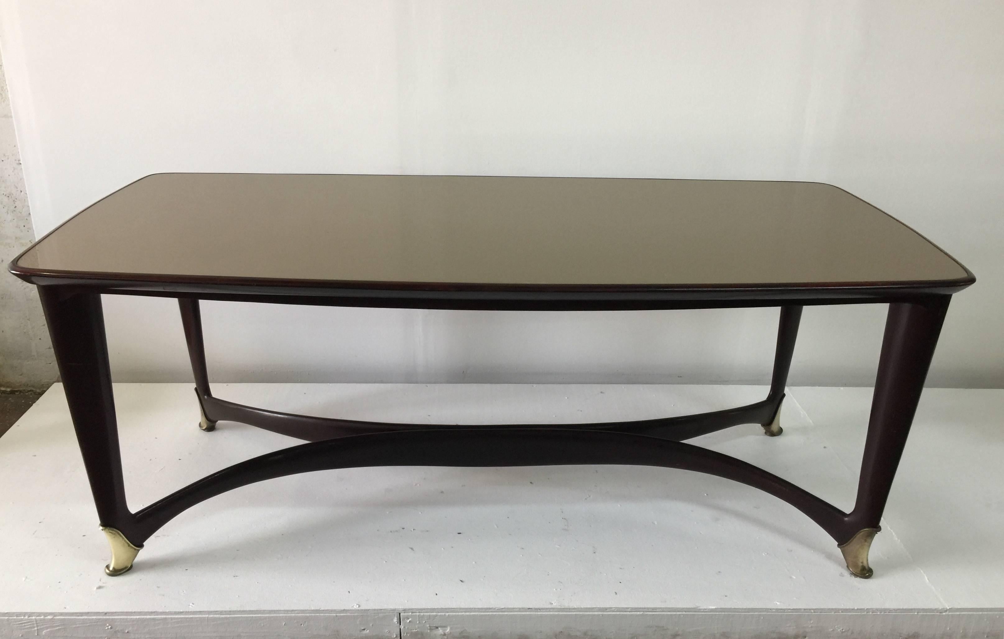Mid-Century Modern dining table designed by Paolo Buffa. Features bowed stretchers, original reverse painted plateau and original brass sabots (boots).