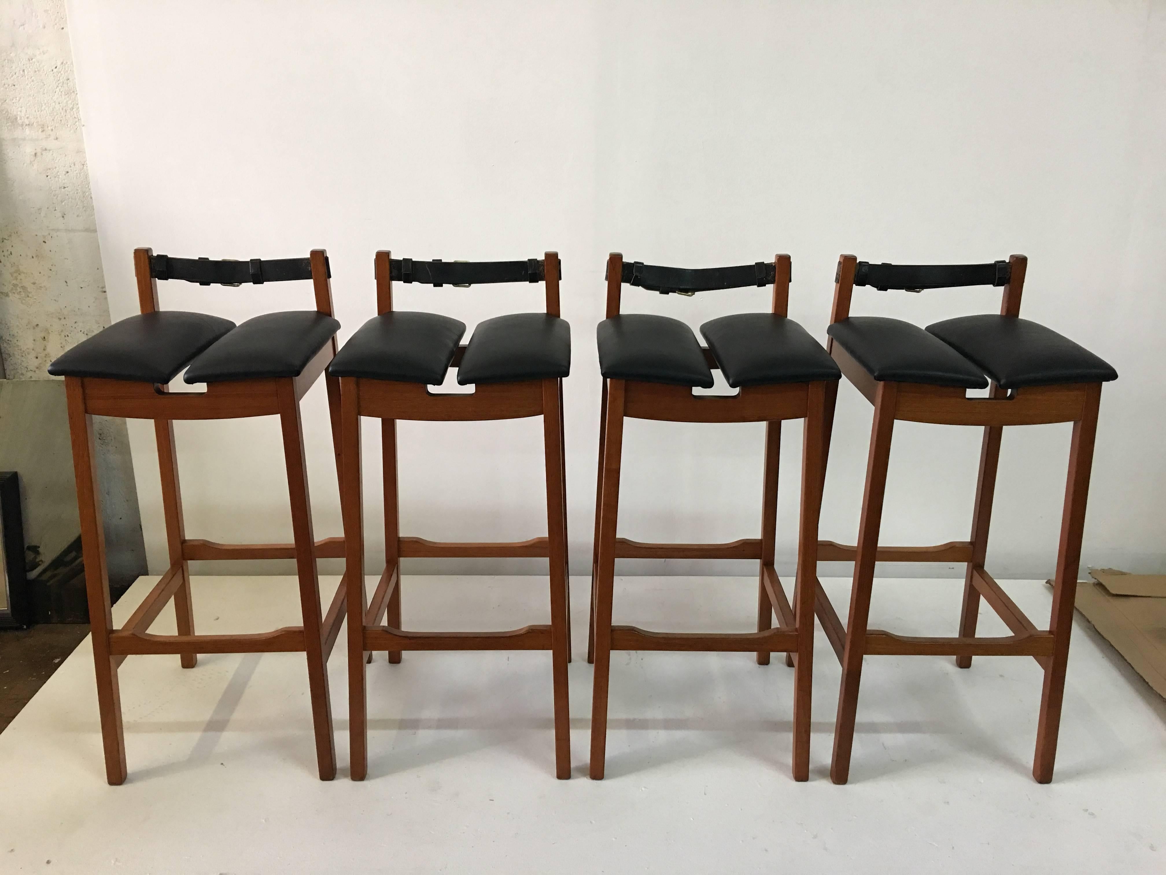 These vintage bar stools feature masculine lines, a black leather worn belt strap as a backrest and newly upholstered black leather hide seats.