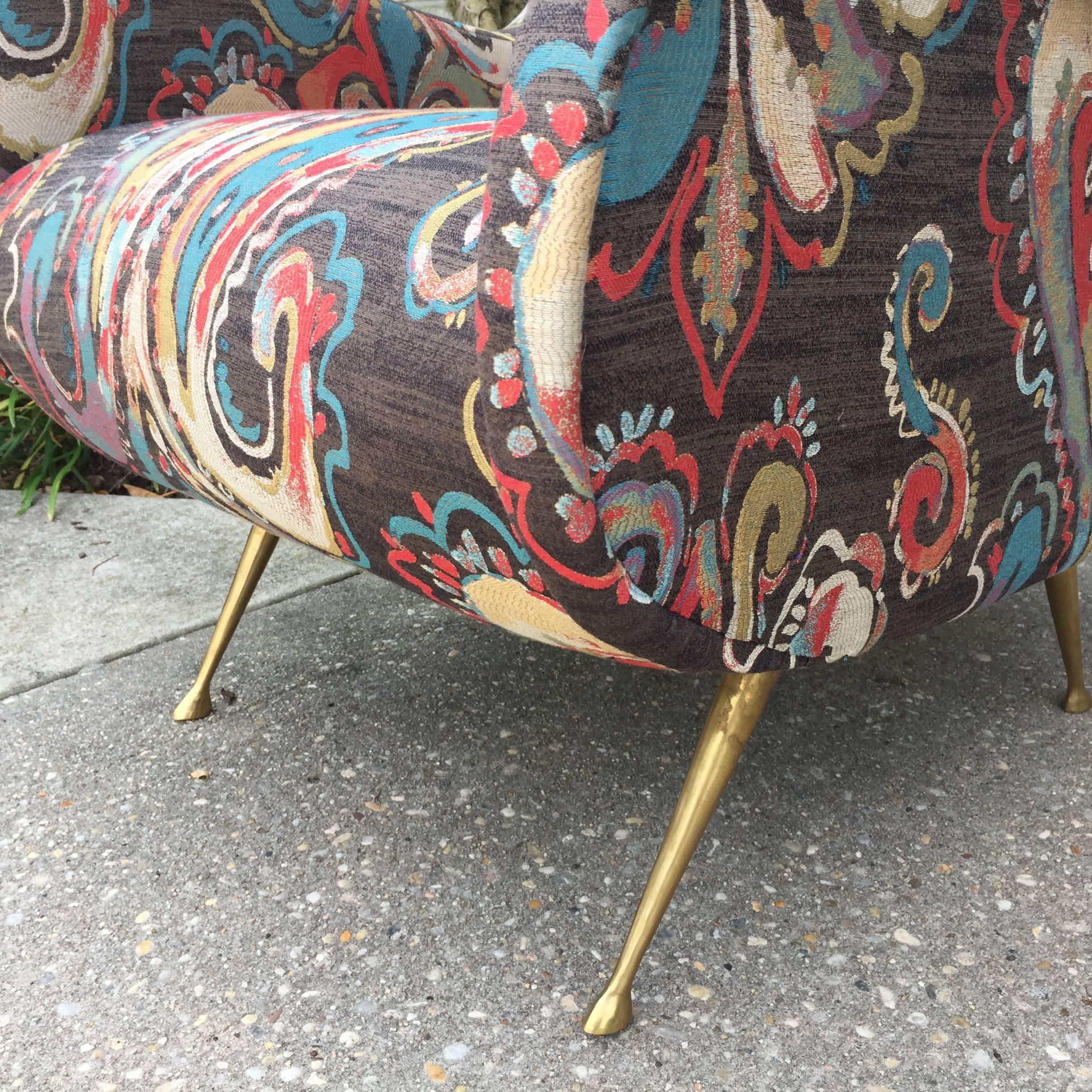 Oversized and whimsical pair of vintage Italian armchairs in the style of Marco Zanuso. The fabric is a stylized paisley with corals, turquoise and browns.

Brass tapering legs have feet to base.