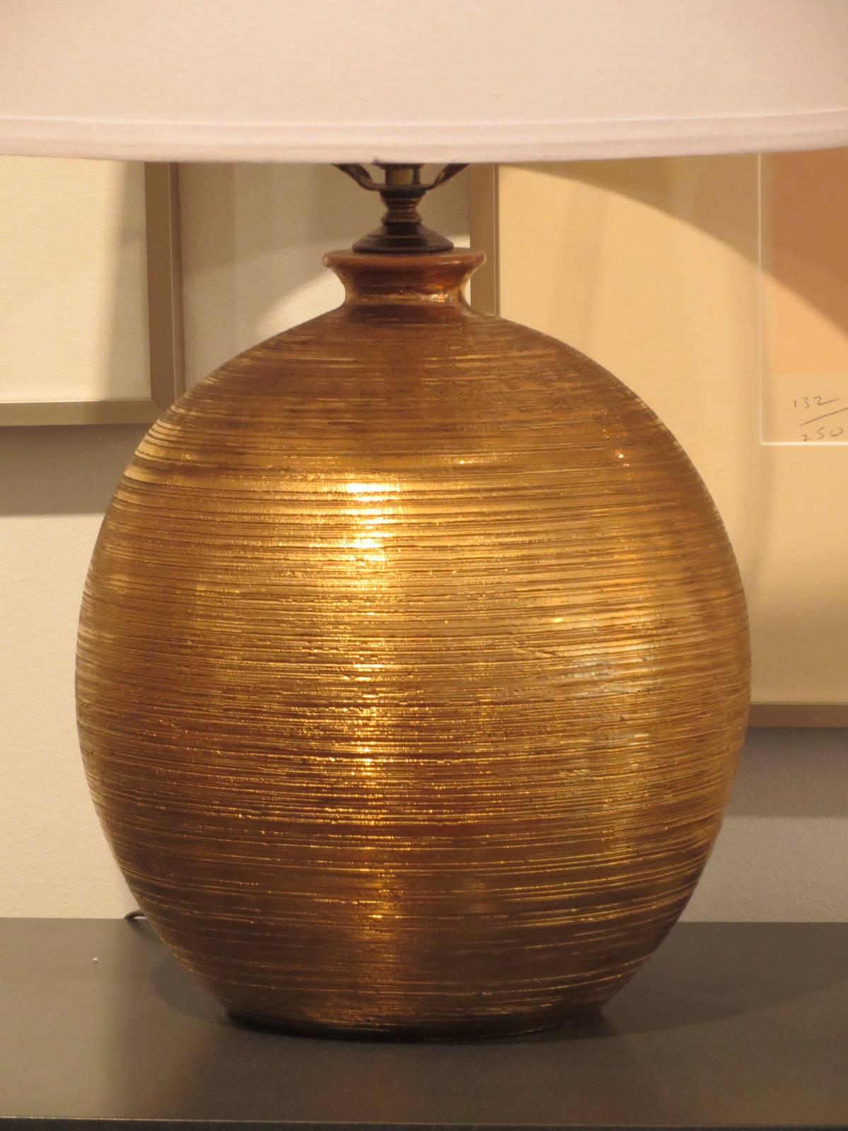Striking 1960s table lamp, hand thrown by Bitossi. Glaze is 18-karat gold. The lamp was made for the Bergbaums Store in Sweden. Height includes shade.