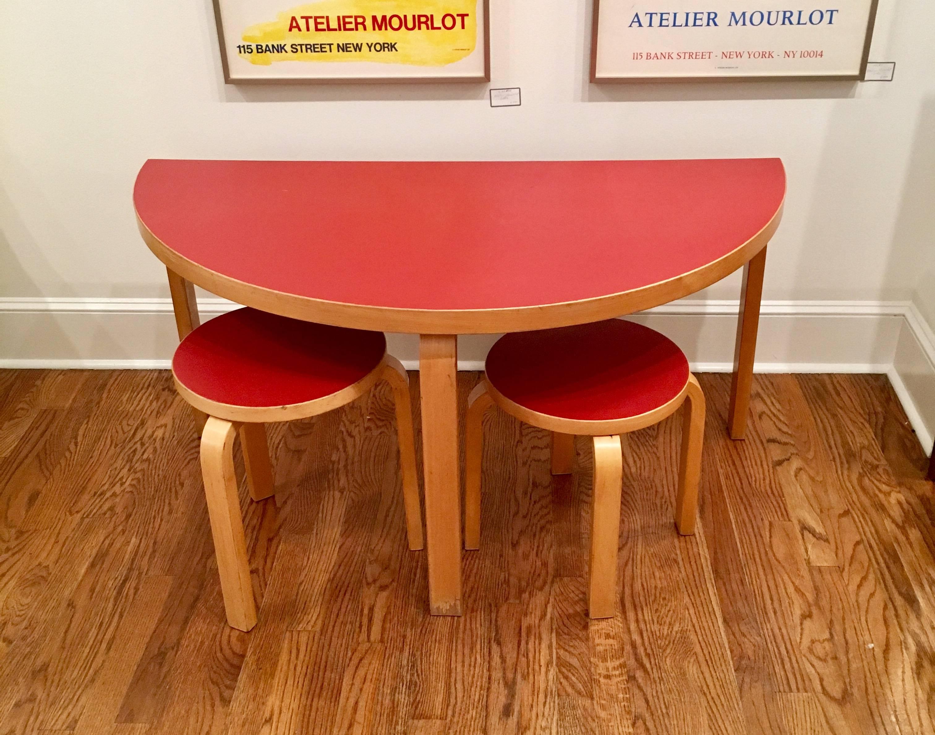 Vintage Alvar Aalto model 95 children's circular table and two stools. Manufactured by Artek of Finland. All pieces are made of birch wood and have red Formica tops. Tops have been refinished. Measurements of the two stools are 13.5