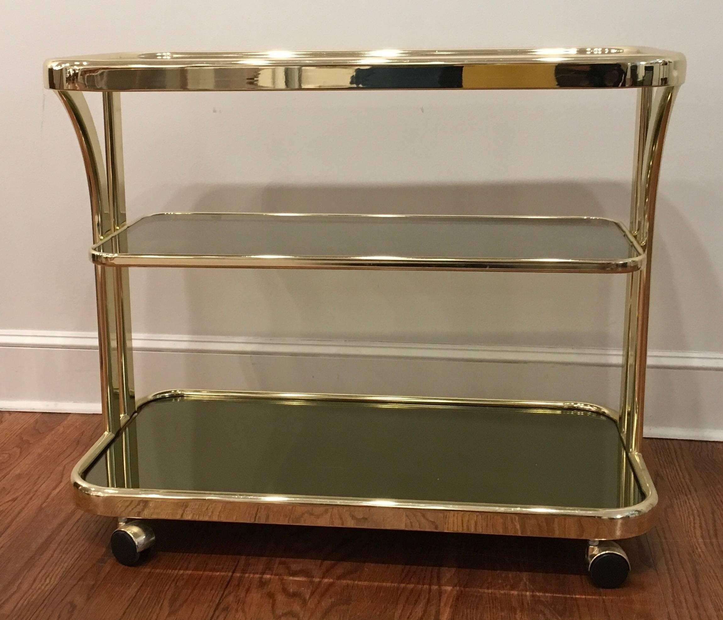 Morex Italian brass bar cart on castors with smoked glass for the two top shelves and mirrored glass on the bottom. Three tiered bar cart allows for great serving and storage.