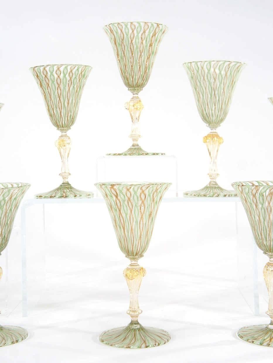 A fabulous and rare set of 12 Venetian  hand blown goblets with apple green, white and aventurine latticino bowls and foot. The stems are swirled and filled with gold leaf inclusions and have applied prunts. The size is large and useful and would