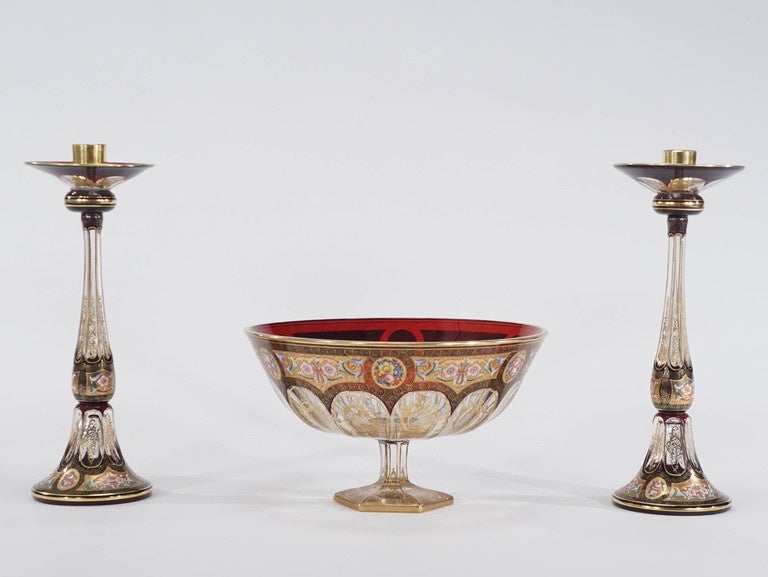 This is a striking and dramatic centrepiece consisting of a large footed centre bowl and two matching candlesticks. Each piece is cased in ruby red overlay and cut to clear revealing 12 teardrop panels surrounding the hexagonal stem and foot.