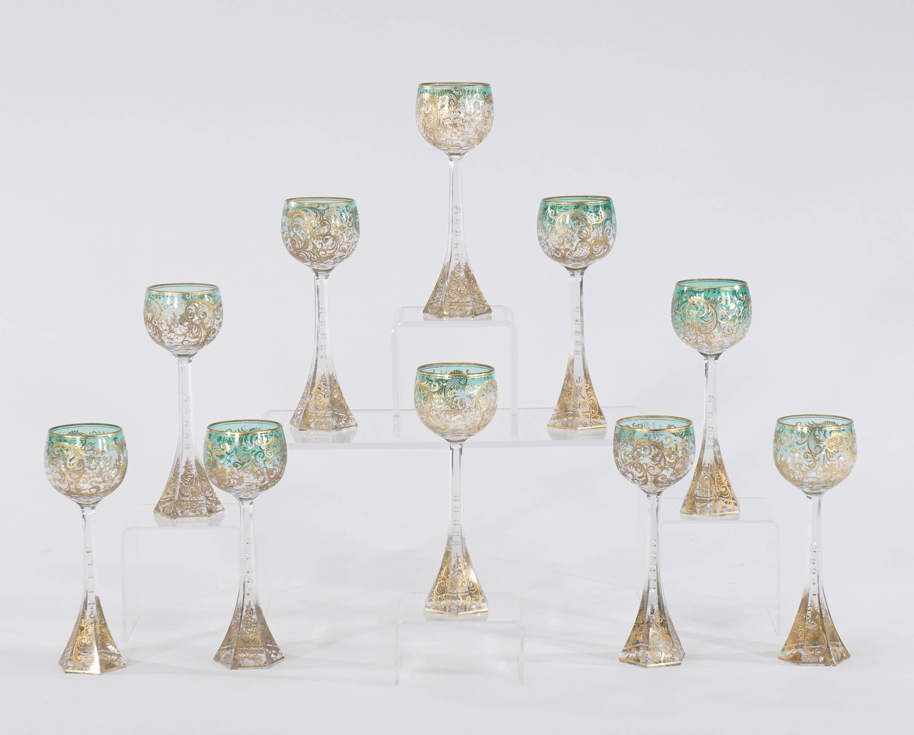 This magnificent set of ten Moser 19th century wine goblets feature a subtle aqua green shaded to clear bowl with intaglio cutting and embellished with raised paste gold. What sets these apart is the tapered and elongated stem, terminating in a