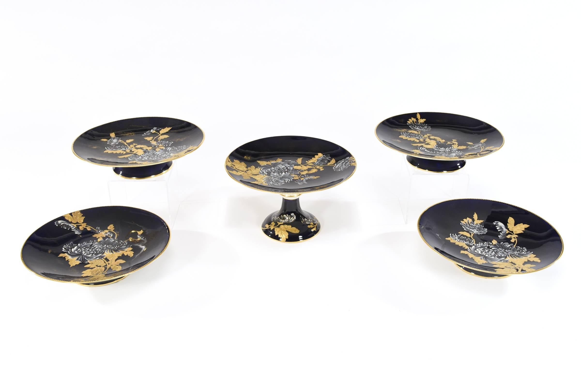 Made by the renown English porcelain firm of Davenport, this set of ten dessert plates and five serving pieces are all hand painted with a variety of chrysanthemums and foliage. What sets this apart is the fantastic contrast of raised paste gold and