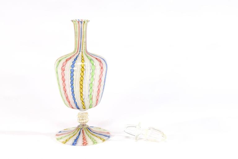 This tall handblown decanter was made in Murano and exhibits the master glassblowing techniques of Salviati. The alternating multicolor and gold latticcino canes encircle the body and foot with a gold leaf infused connector and stopper which creates
