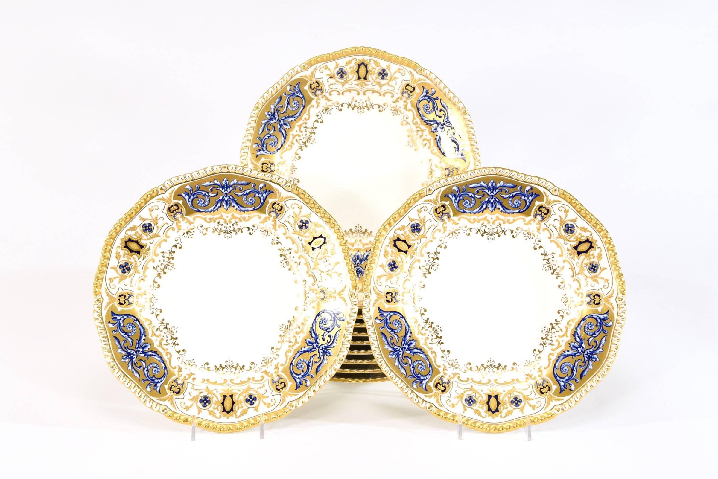 A set of 12 rare Coalport, made for Tiffany and Co. dinner plates featuring six alternating reserves of two colors of cobalt blue enamel with profuse raised paste gold overlay. The plates are framed by a gilded gadroon border. The exquisite