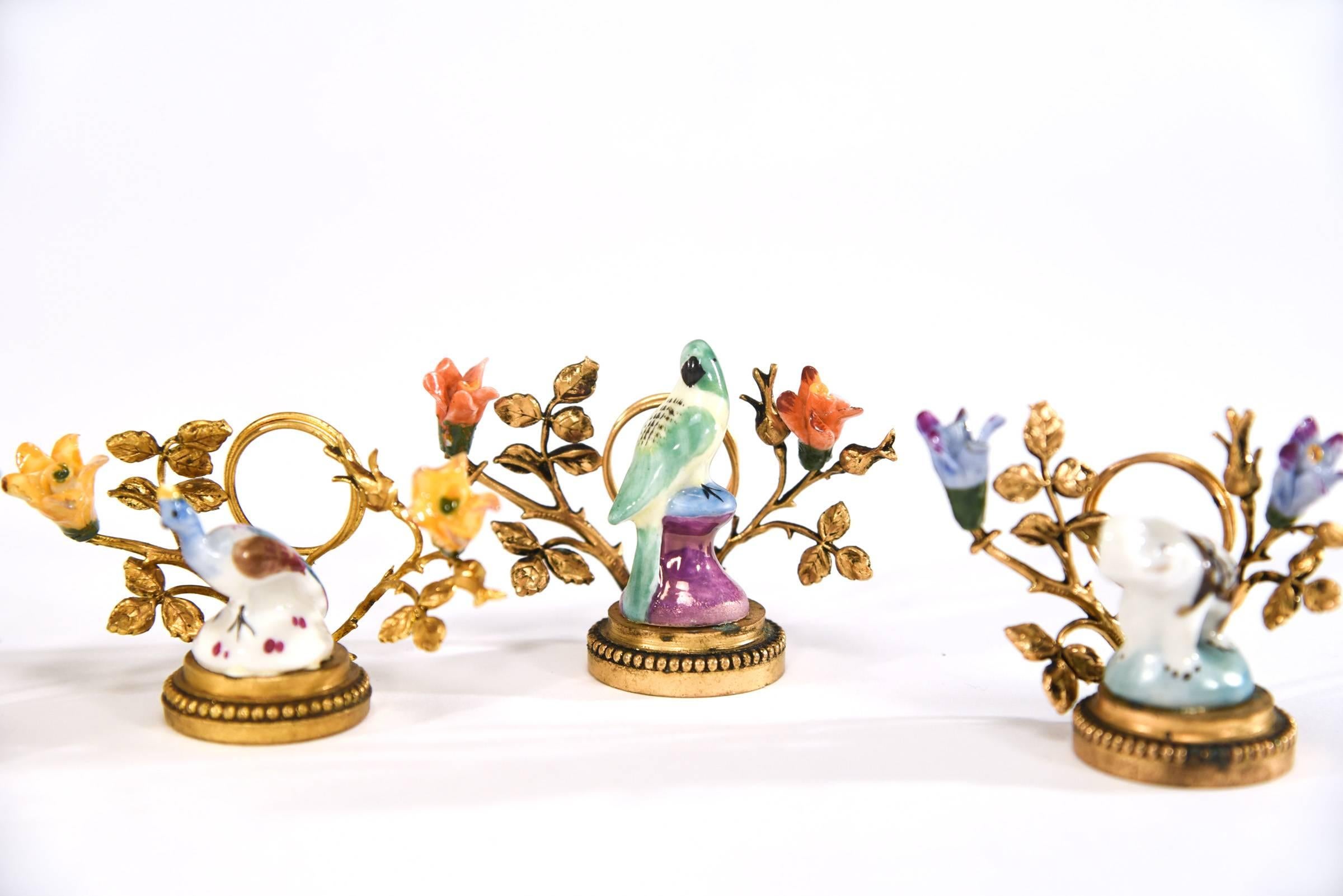 Este raro juego de 12 tarjeteros de porcelana está montado sobre bases de bronce con patos, pájaros, elefantes y mucho más de porcelana. También están adornadas con flores de porcelana y llevan la inscripción 