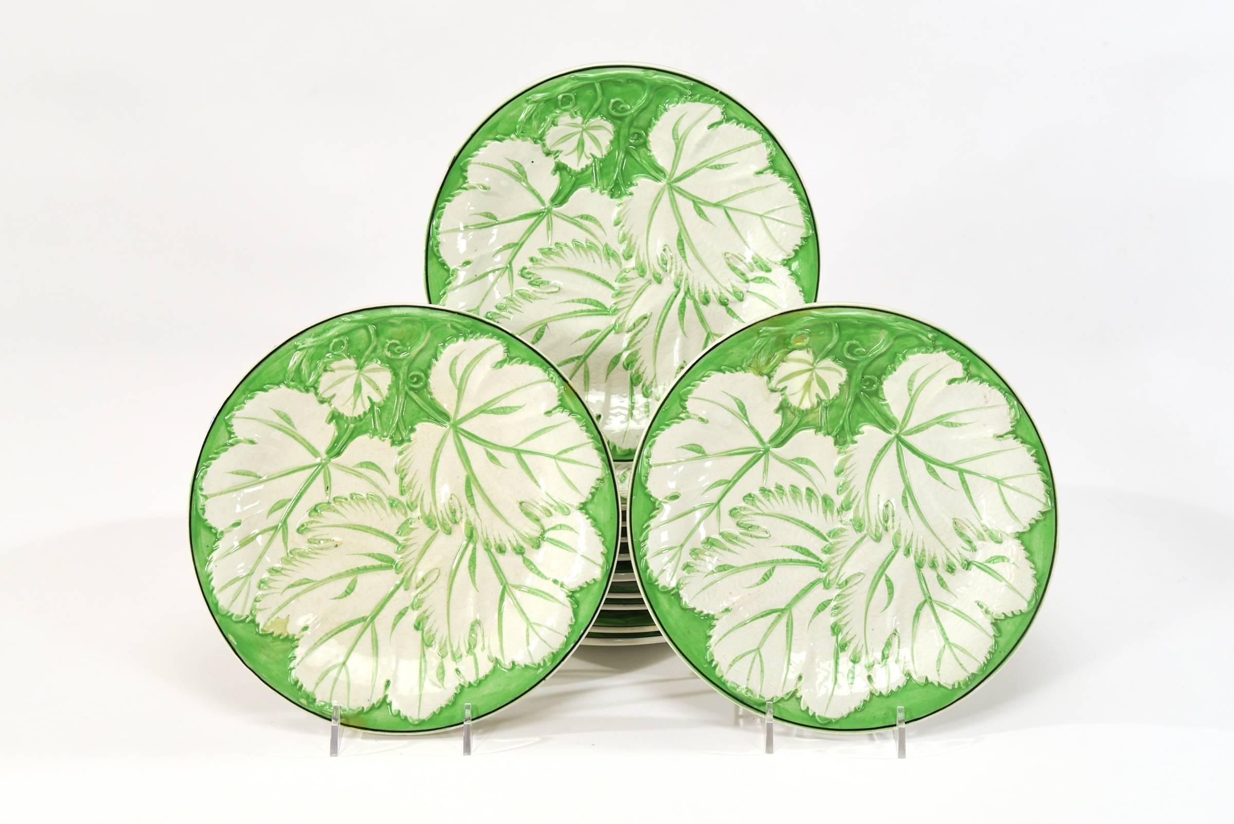 Casual yet elegant, this English dessert service features 14 dessert plates and two footed serving pieces ready for summer entertaining. Dating from late 19th century. These have a molded grape leaf decoration on a bright apple green enamel ground.