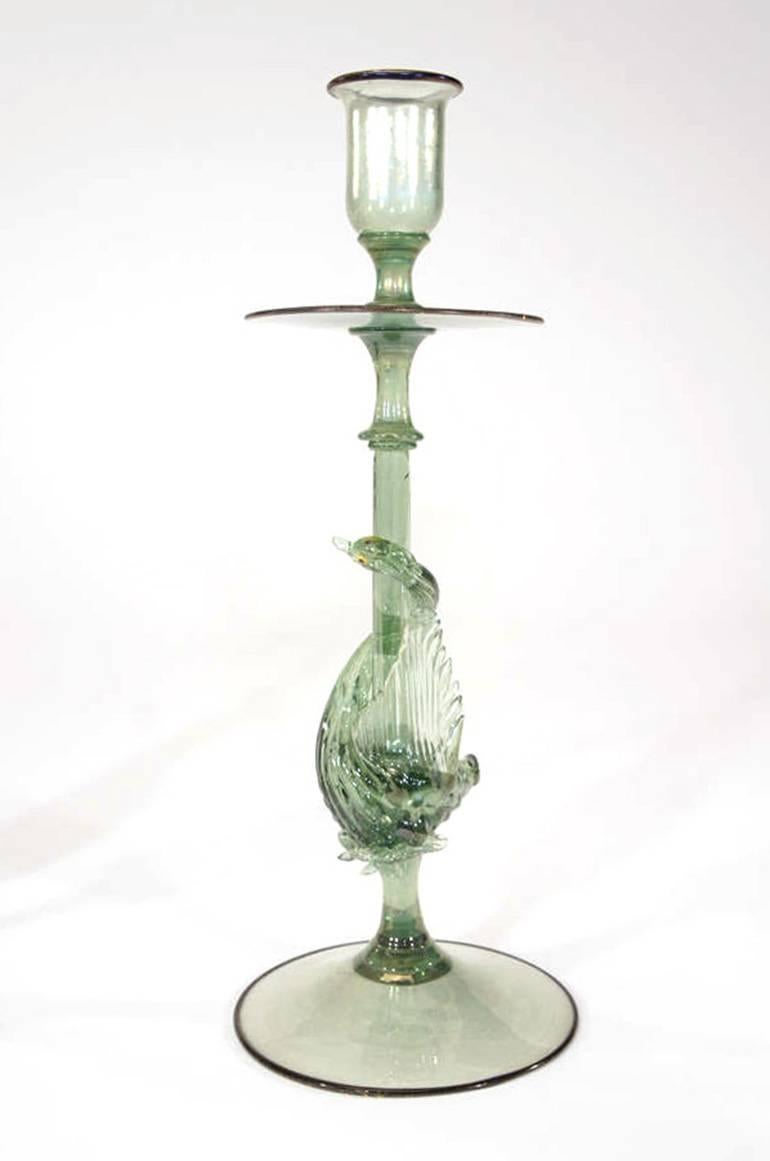 This pair of hand blown candlesticks are made of a very unusual green with a subtle iridescence featuring a charming swan connector who is encircling and peeking around the stem. Tall and elegant, they are trimmed in gold leaf infused black glass.