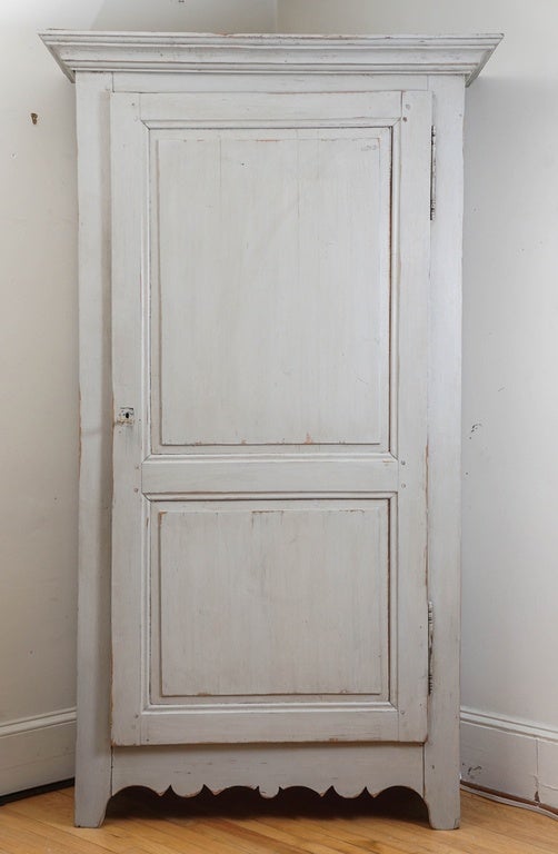 This piece has character, with its scalloped base and wonderful hinges. It’s a large piece but isn't too deep. Painted in a grey color with two shelves inside. There is also a key and lock.