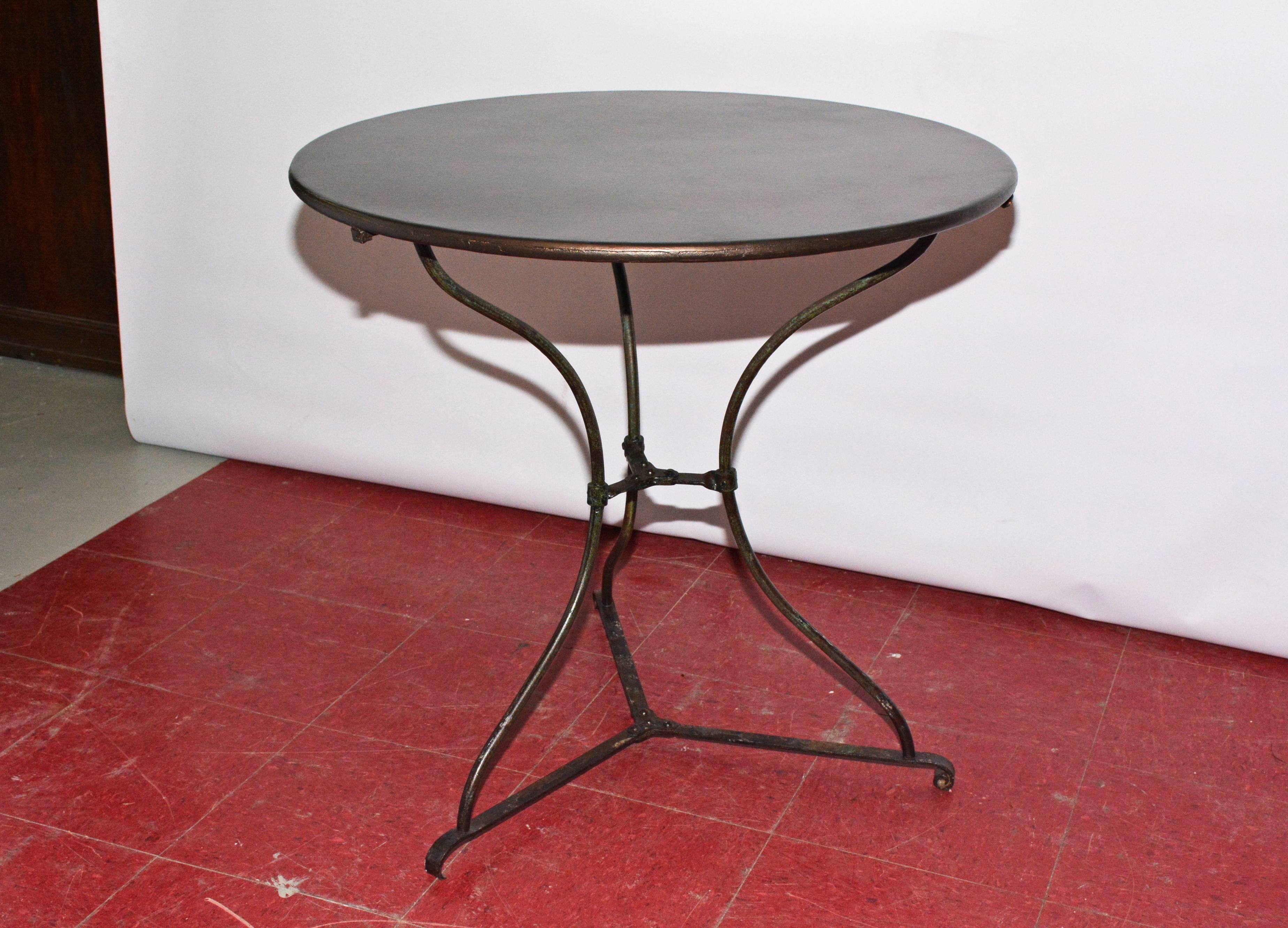 Restored 19th century iron bistro cafe table has a rounded edge with three curved legs joined by an X-form stretcher. Can be used as side table, bedside or sofa table. Also large enough to be used as small kitchen table.