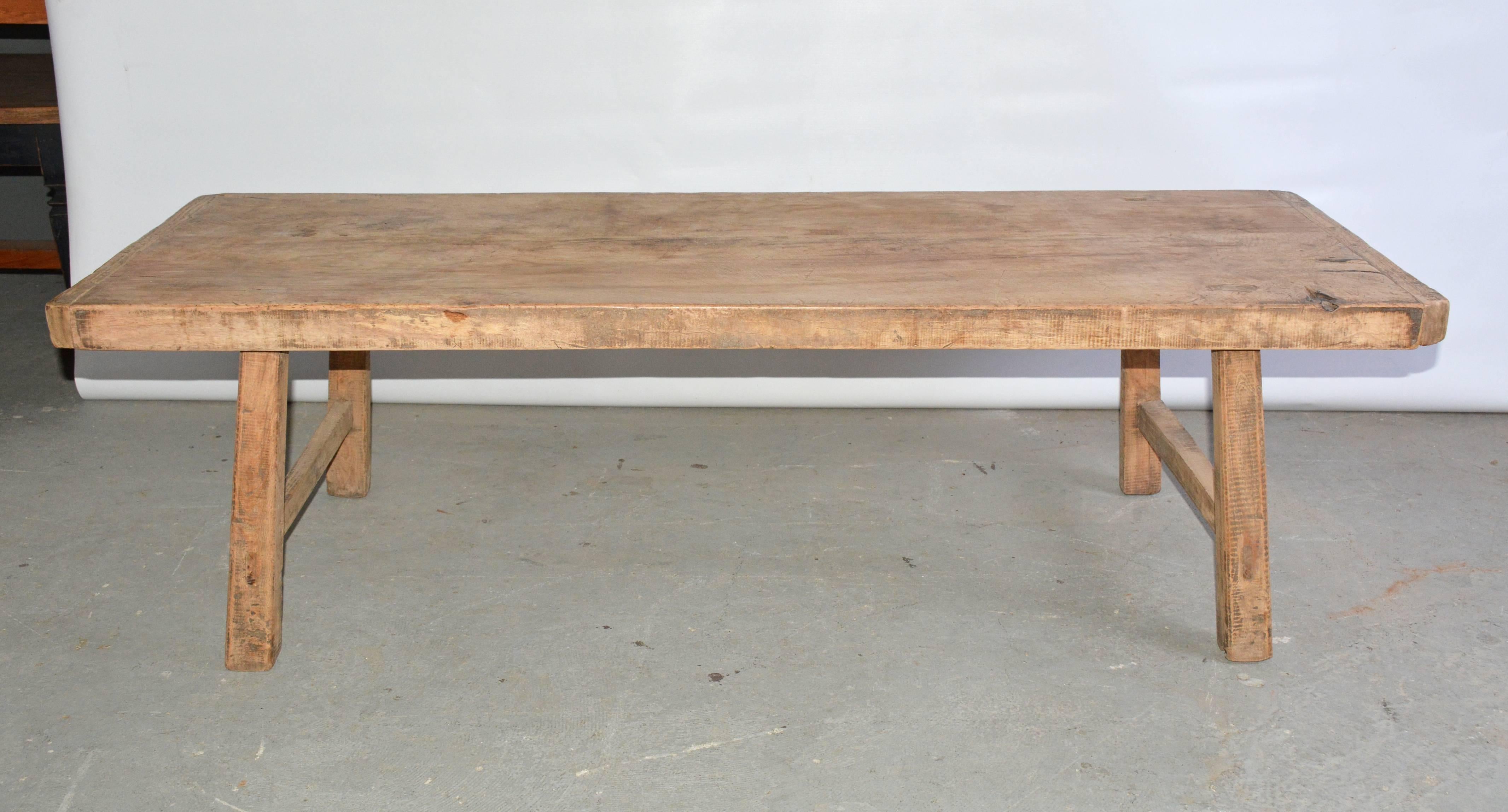 The rustic teak coffee table has angled legs secured with stretchers.