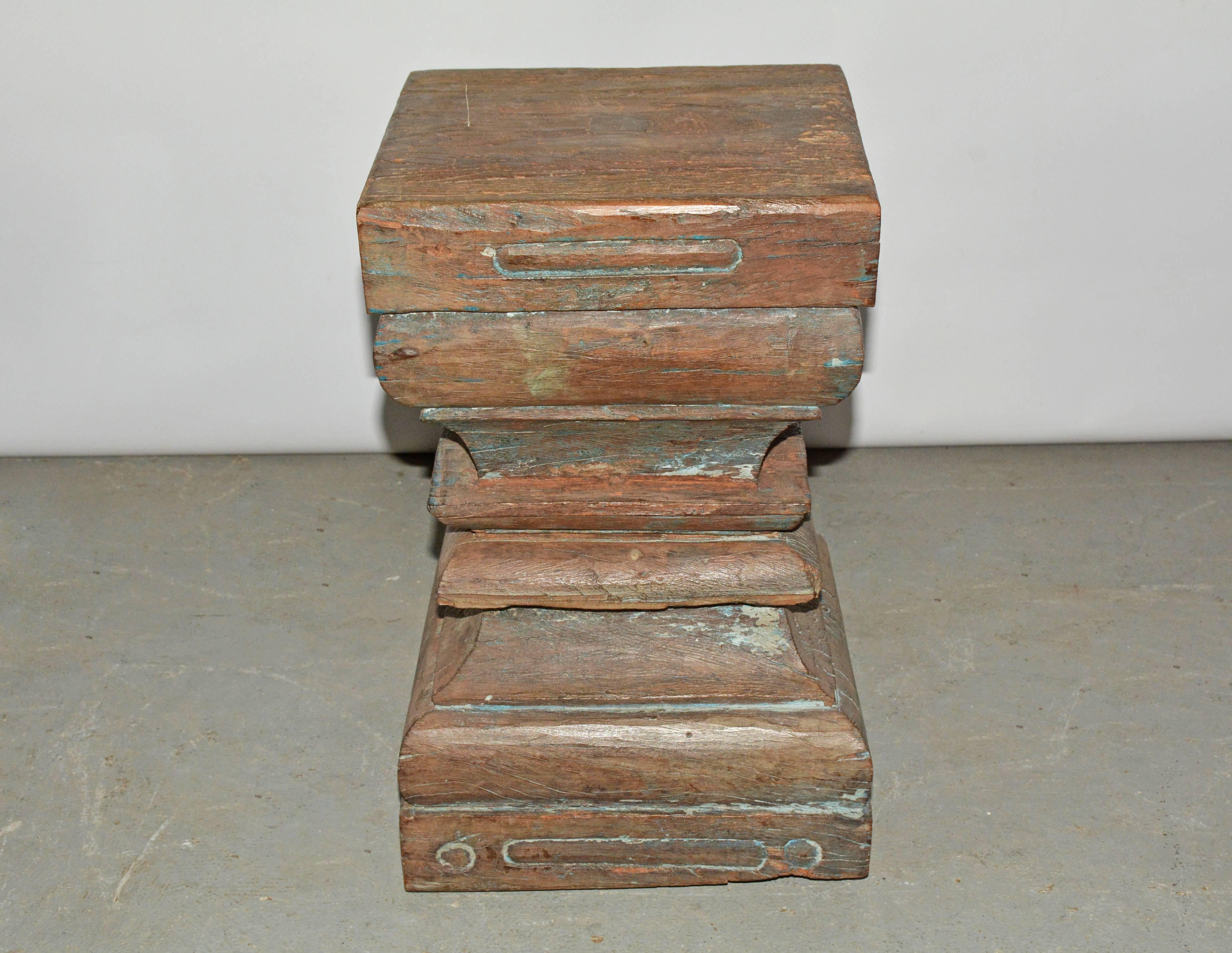 The antique Indian carved wood stool or table has multiple purposes as a stool, side table or stand. The piece is hand-carved, featuring a square shape with an indented waist.