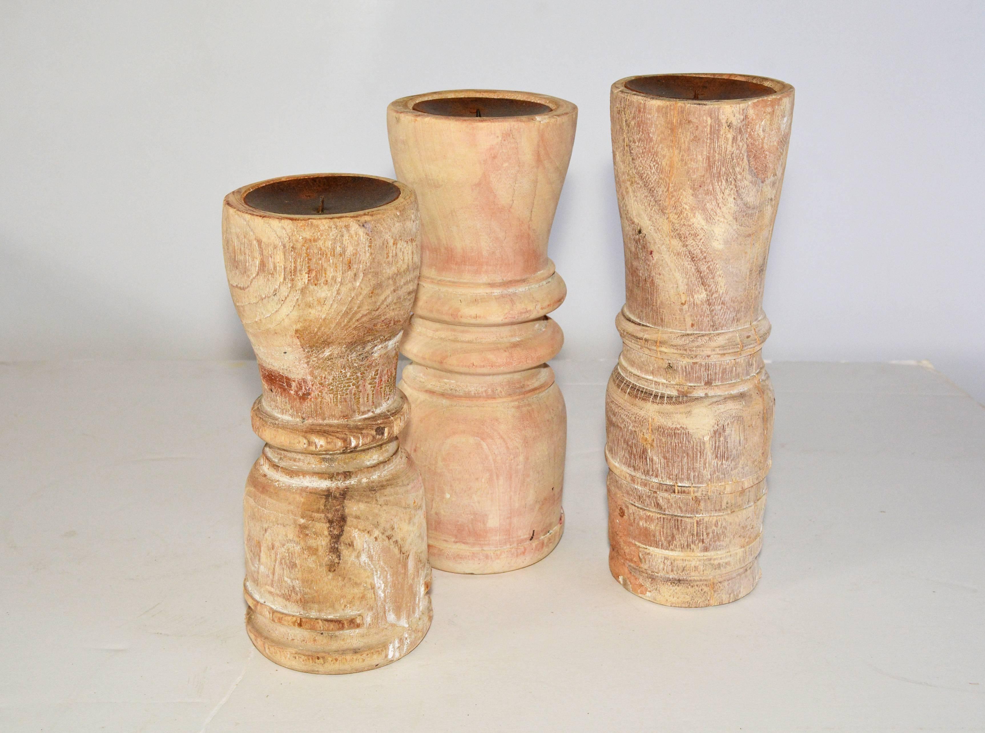 The rustic teak candleholders of three varying heights have concave tops lined in metal with centre spikes to hold fat pillar candles.

Measures: Diameter 4