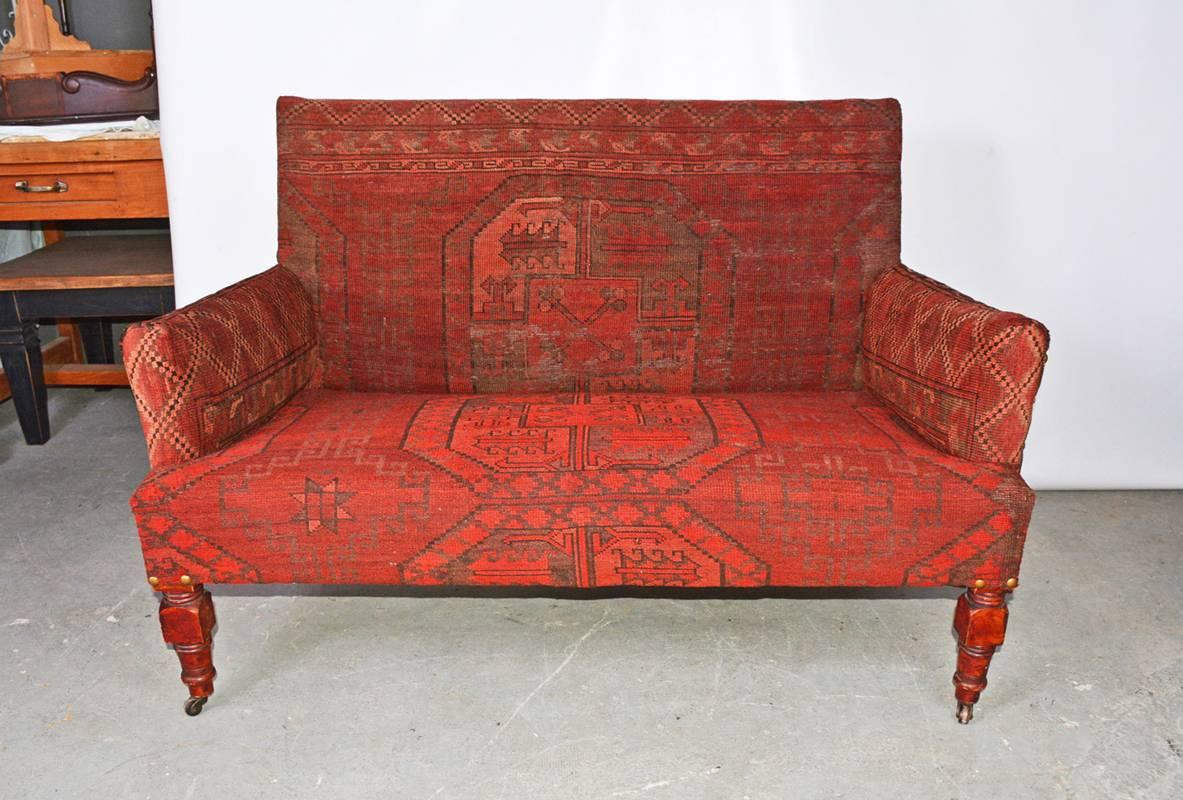 19th century two-seat love seat sofa has been newly upholstered with an antique mideastern carpet.

Measures: Arm height, 22.50