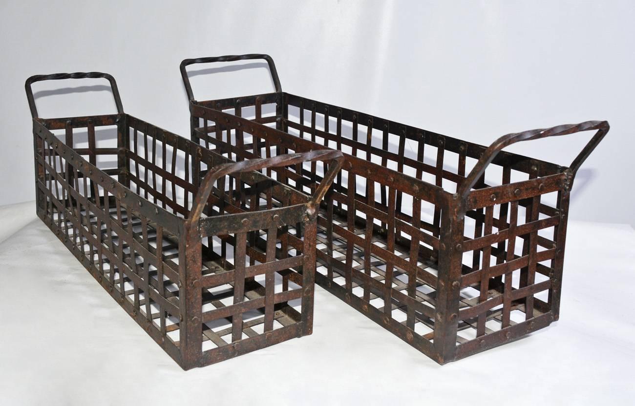 The pair of vintage wrought iron, open-weave baskets or window boxes have decoratively twisted handles and are slightly different in size. The iron strips are attached to the frames with iron studs. Can be sold separately.

Smaller Basket: 26