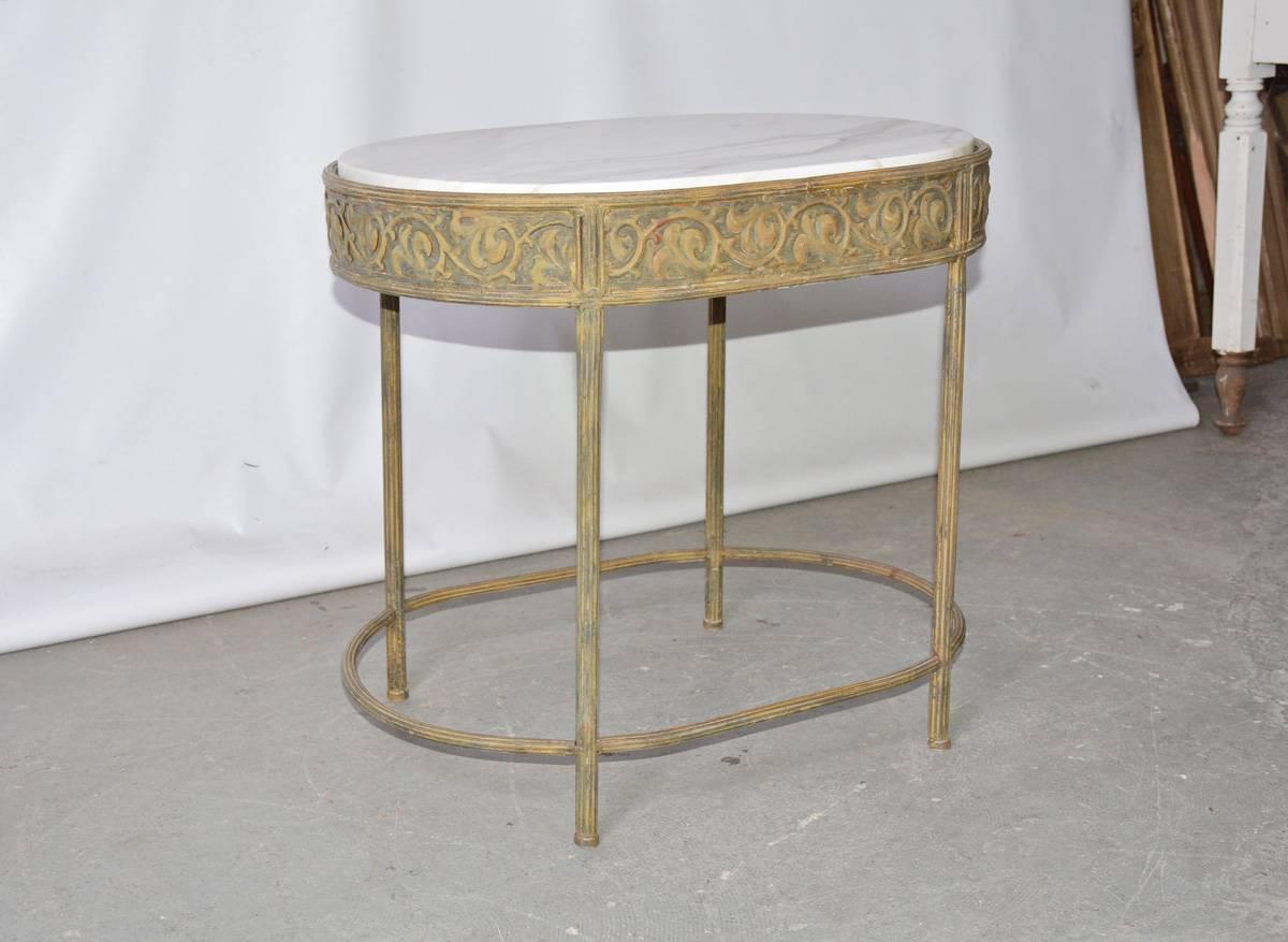 The vintage side table in the neoclassical style has a white-veined Calcutta marble inset top and a gold metal base composed of an apron with vines and leaves en relief and fluted legs and stretchers. Can be used as a indoor or outdoor side table or