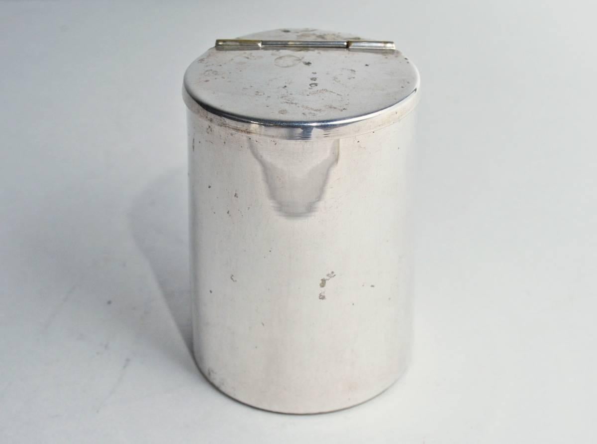 La petite boîte de conserve ou de rangement vintage en métal argenté a un couvercle à charnière.